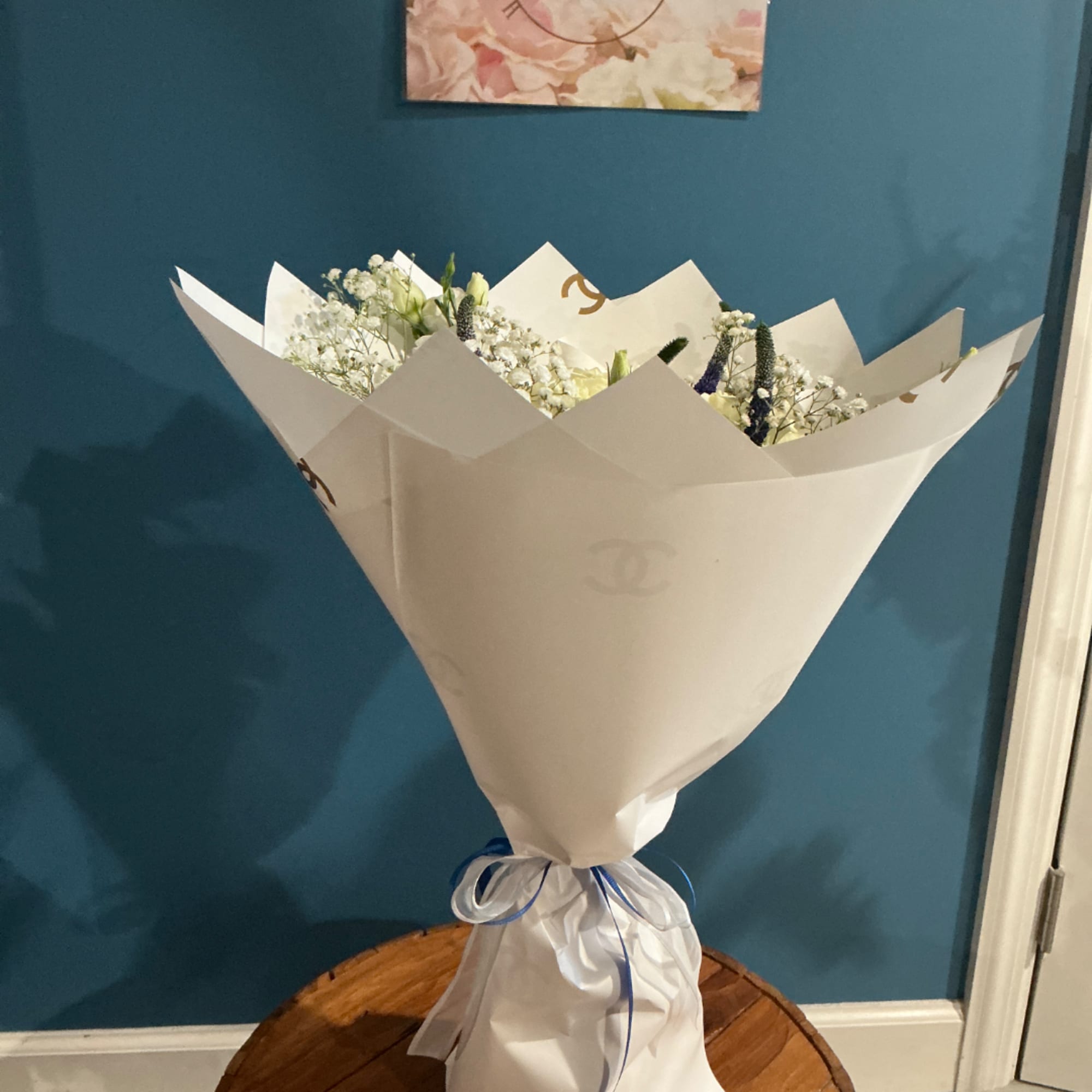White bouquet wrapped in paper with small white and blue flowers.