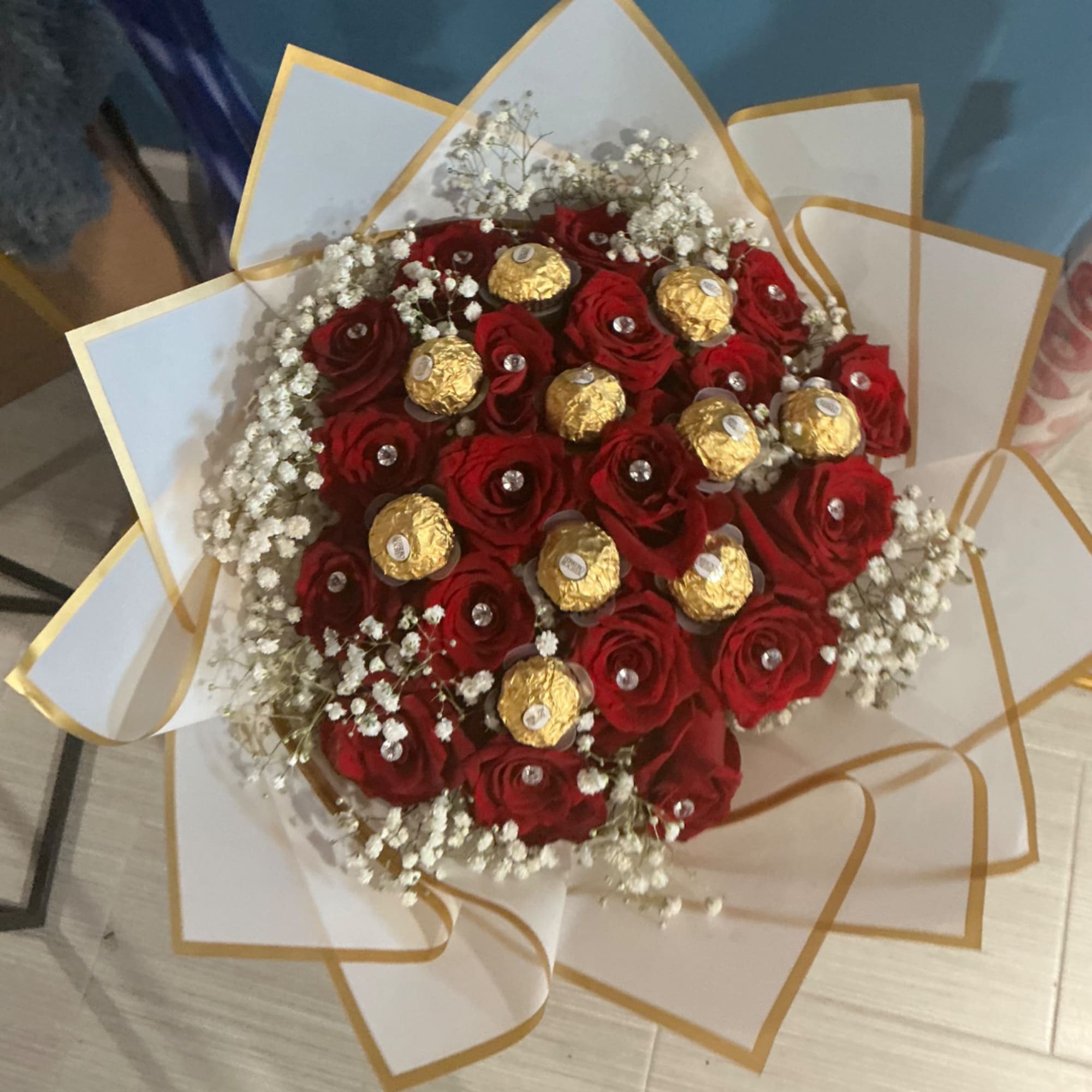 Bouquet of red roses with gold-wrapped chocolates and white baby's breath