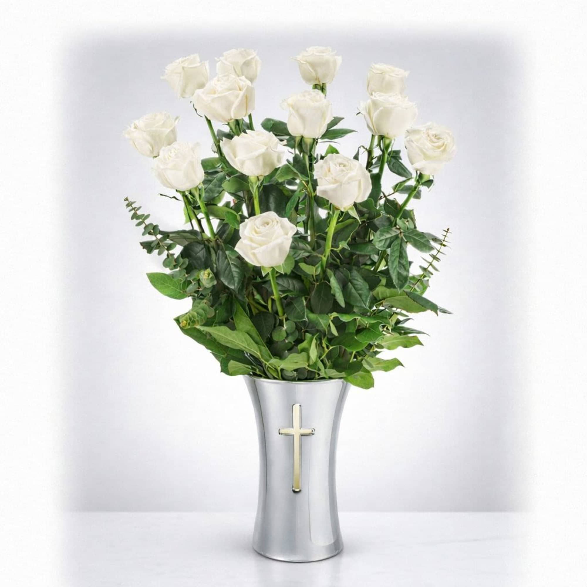 White roses in a silver vase with a cross emblem