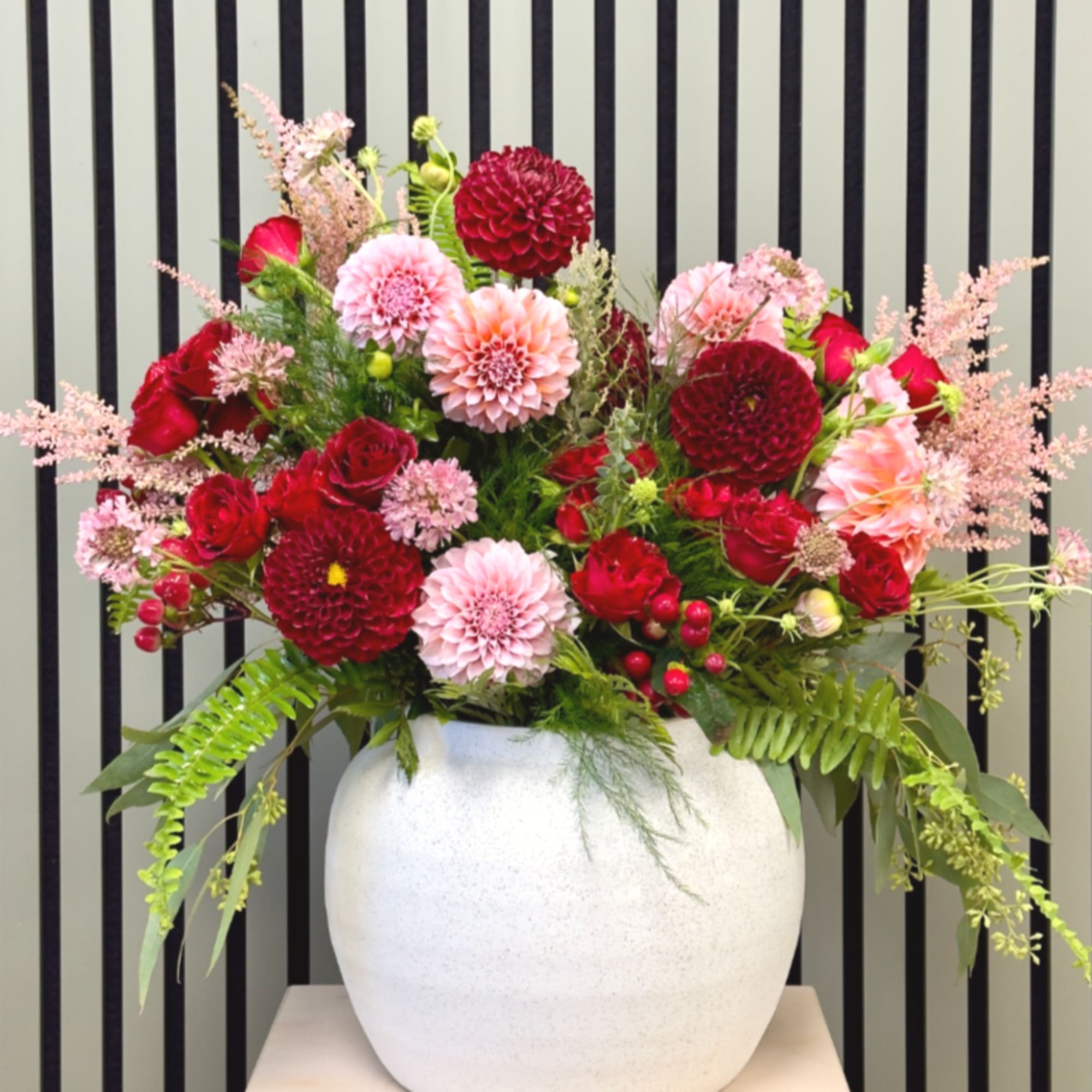 Mixed pink and red flower arrangement in a white vase