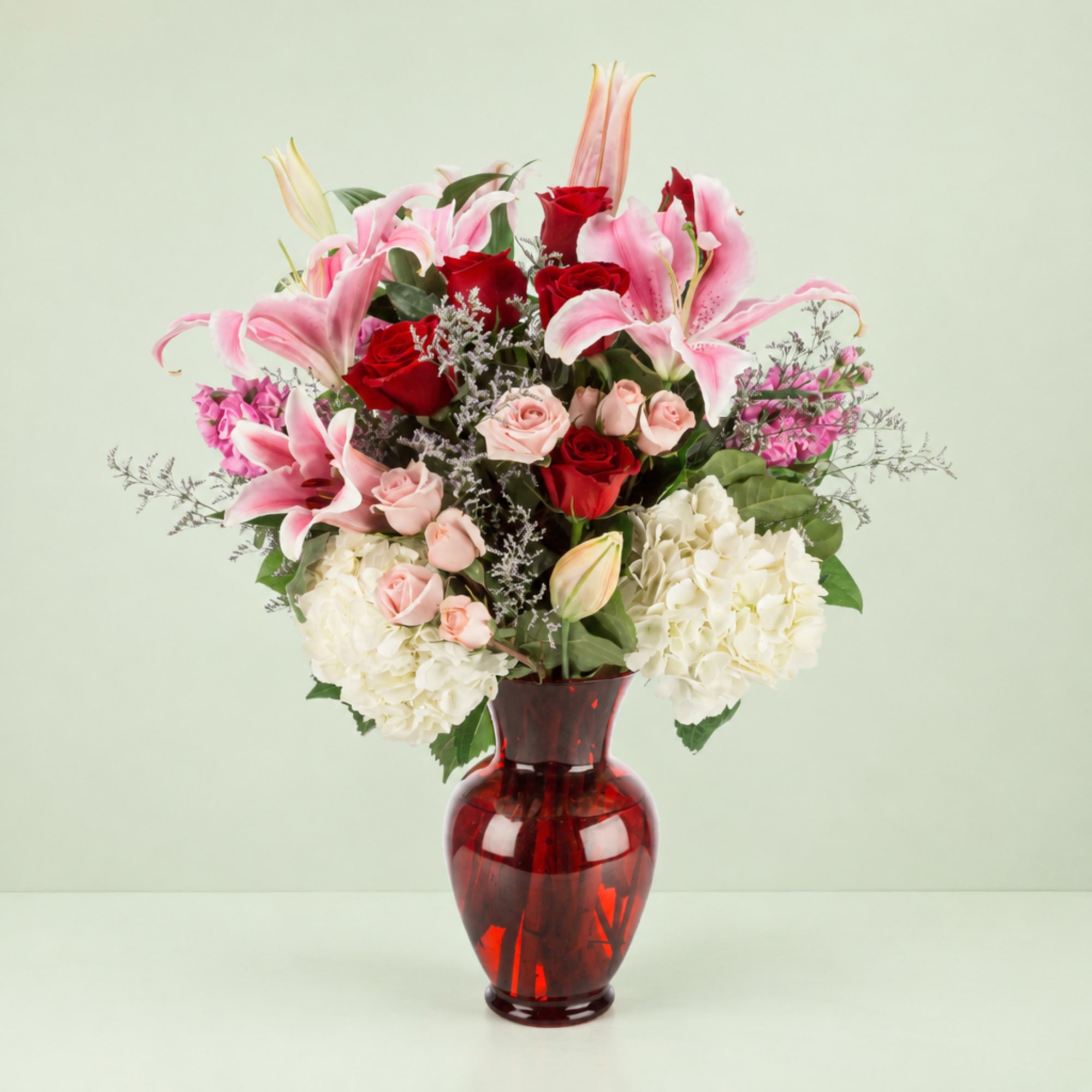 Pink lilies and red roses in a red glass vase