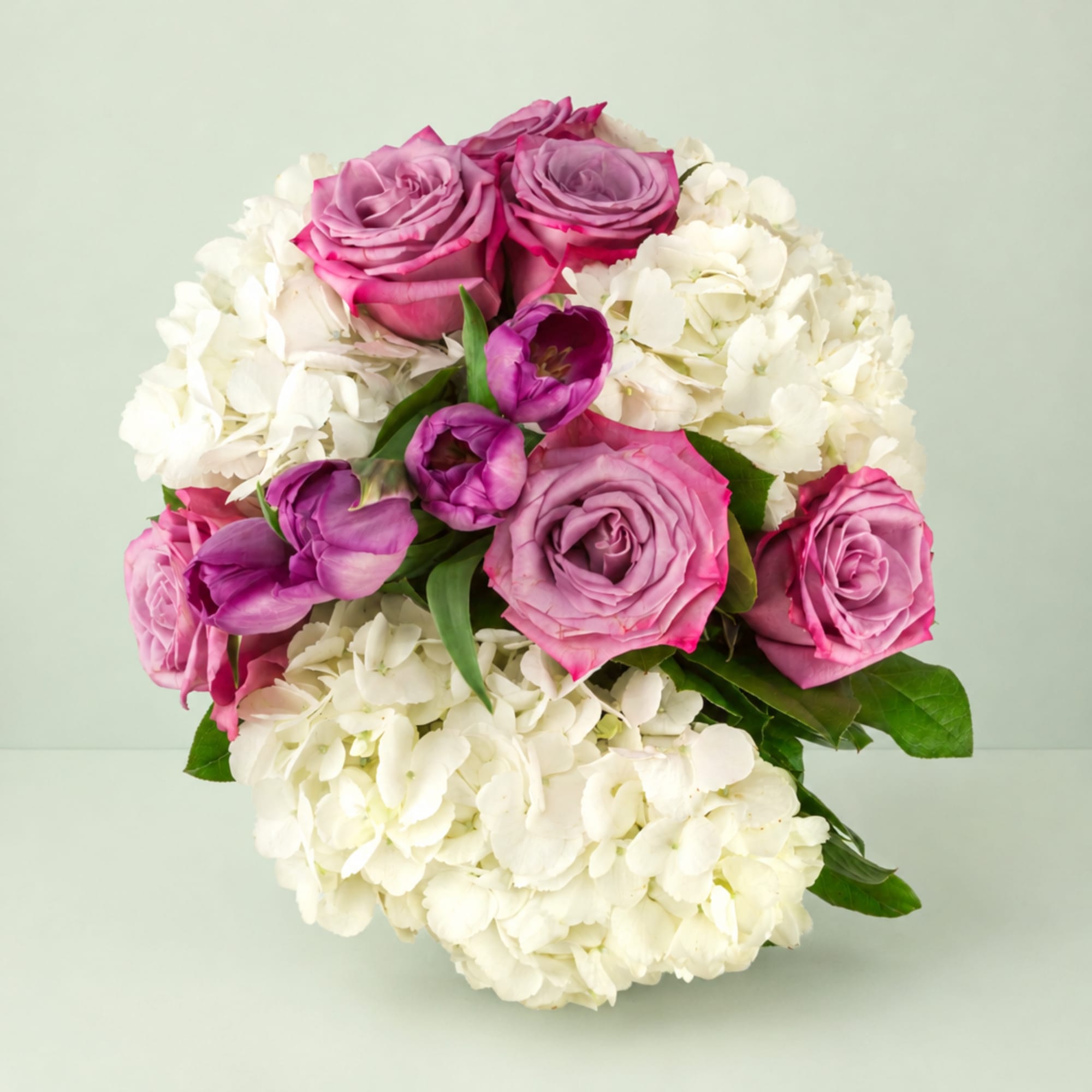 Pink roses and purple tulips arranged with white hydrangeas