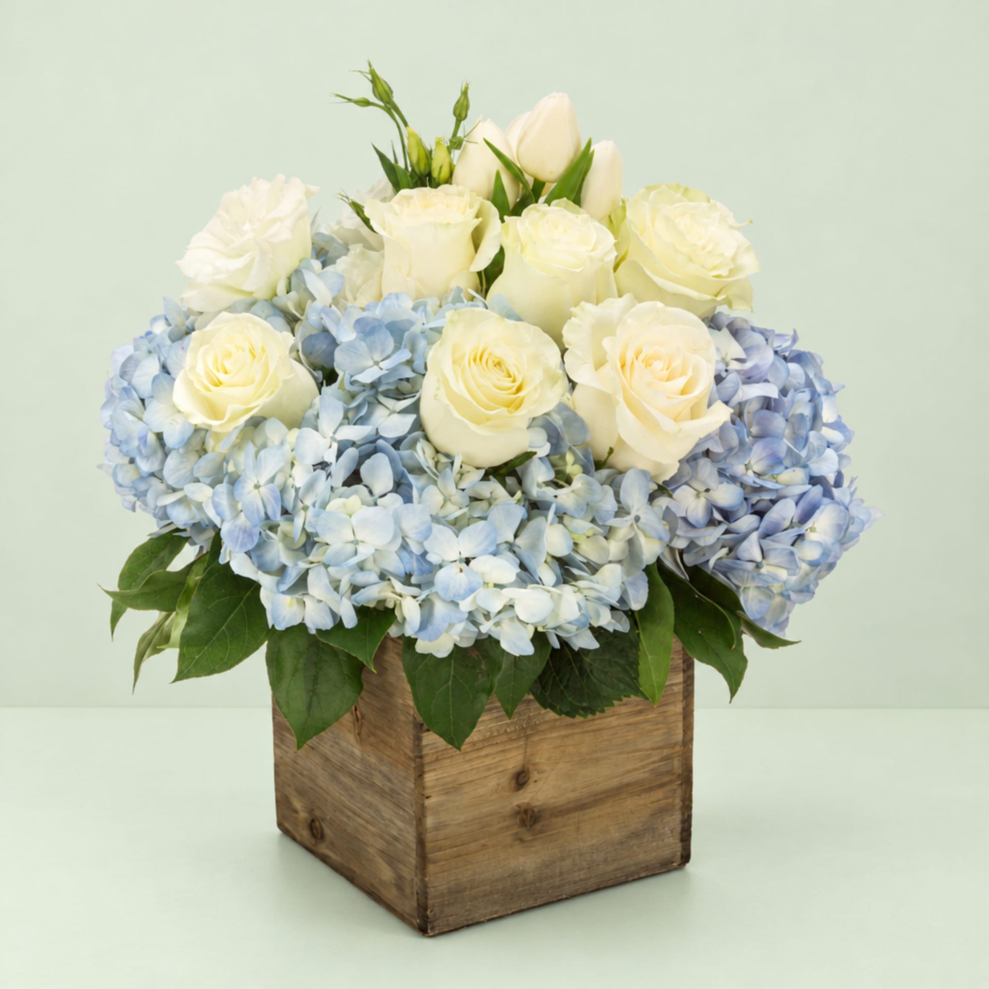 White roses and blue hydrangeas in a wooden box