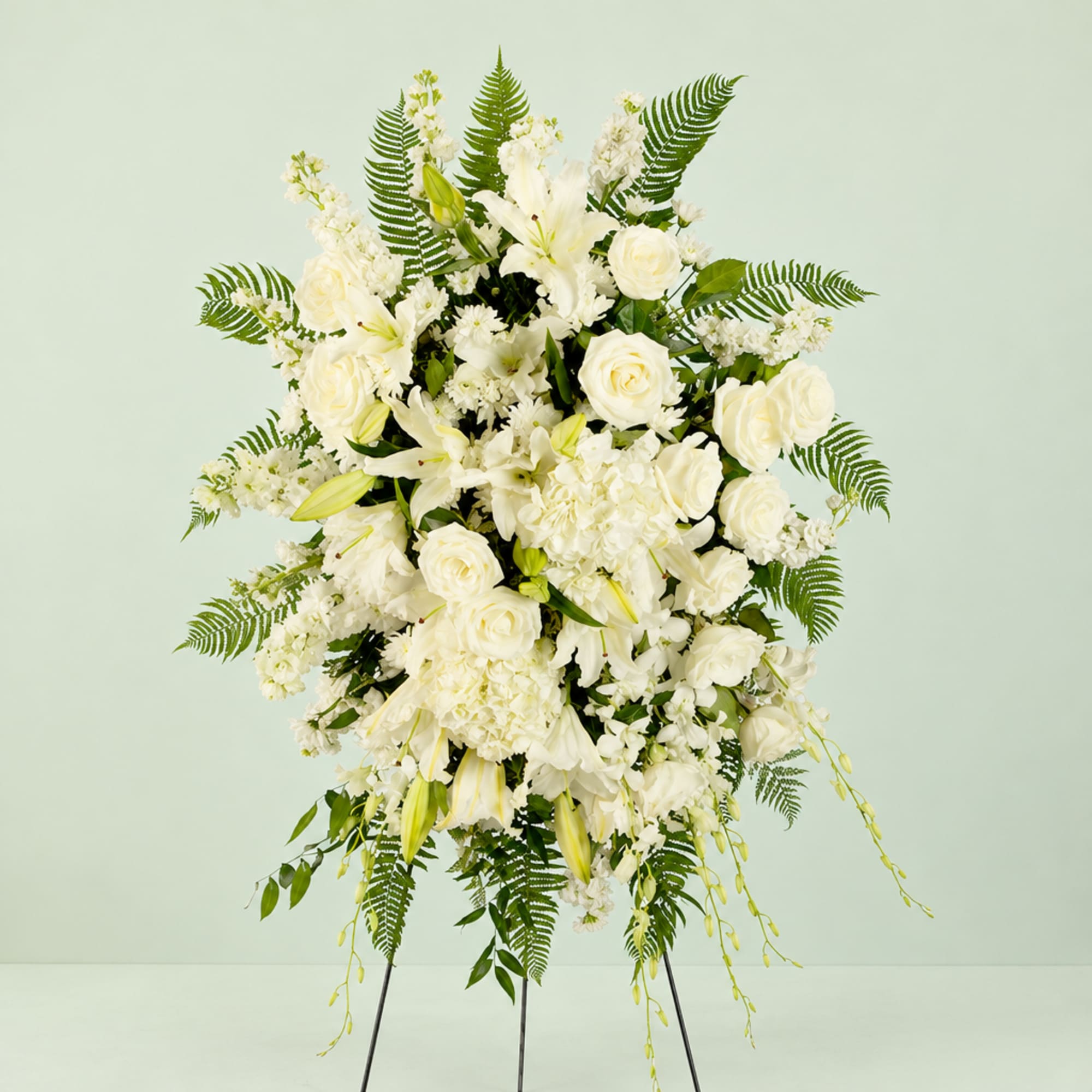 White floral standing spray with roses, lilies, and ferns