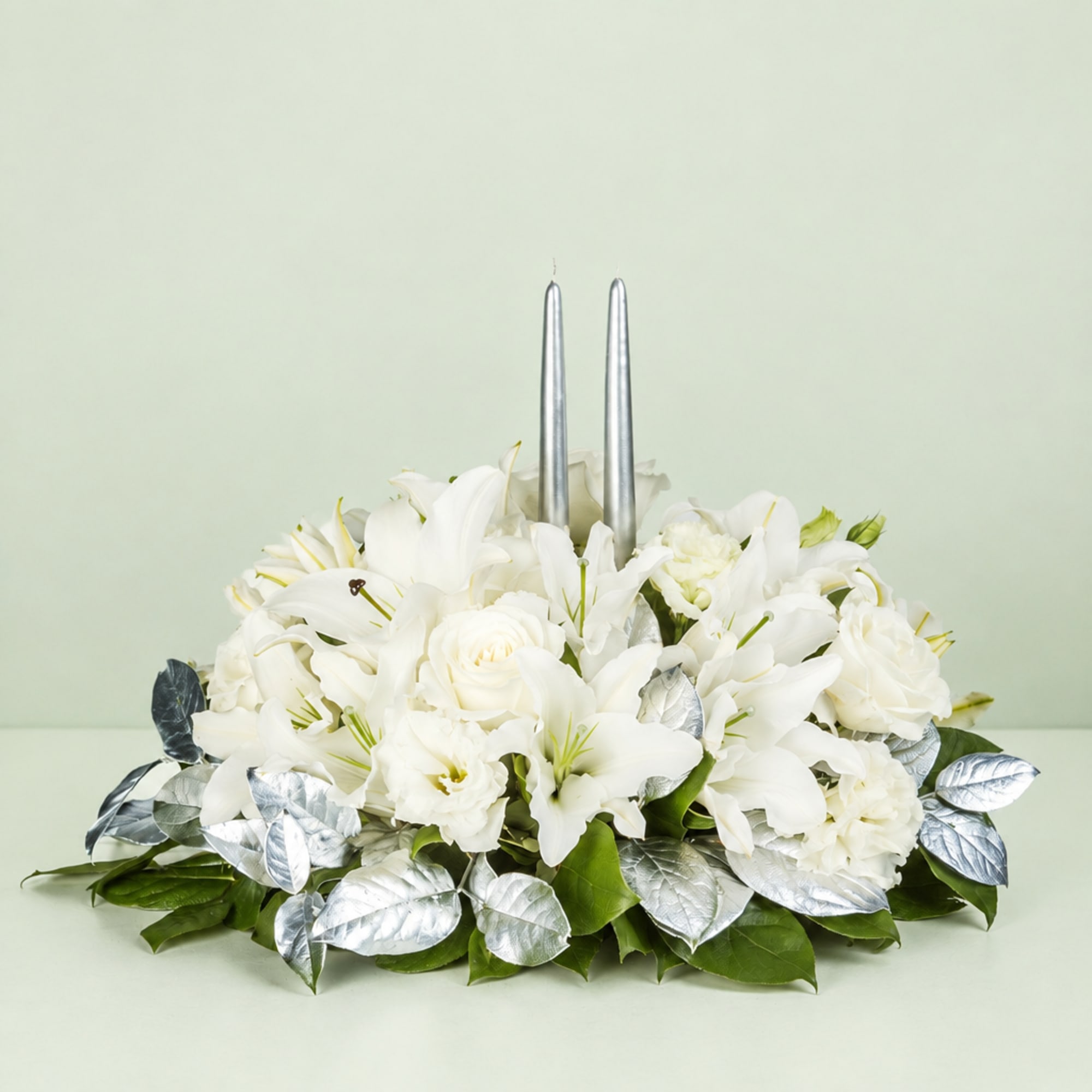White floral centerpiece with two silver taper candles