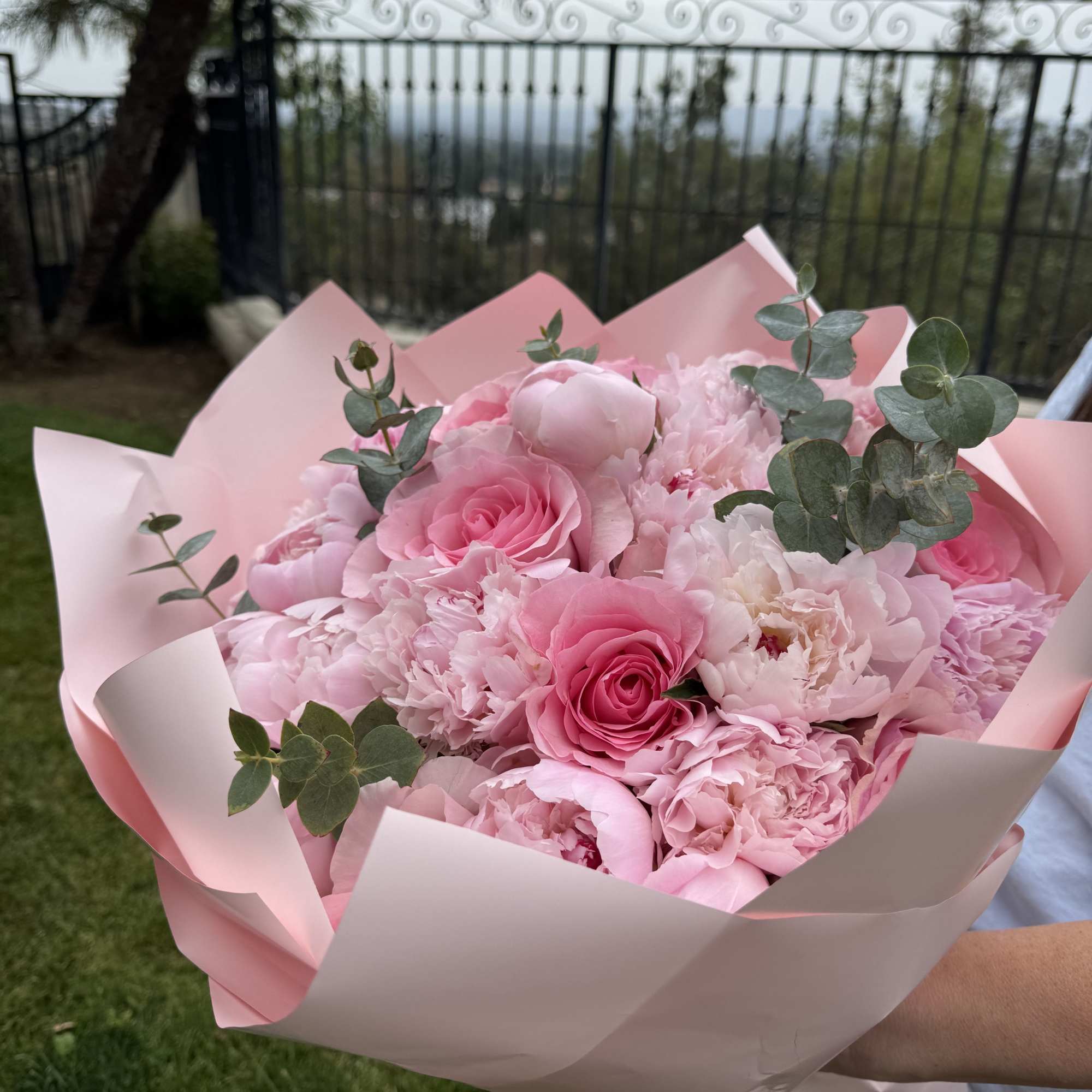 Pink bouquet of roses and peonies wrapped in pale pink paper