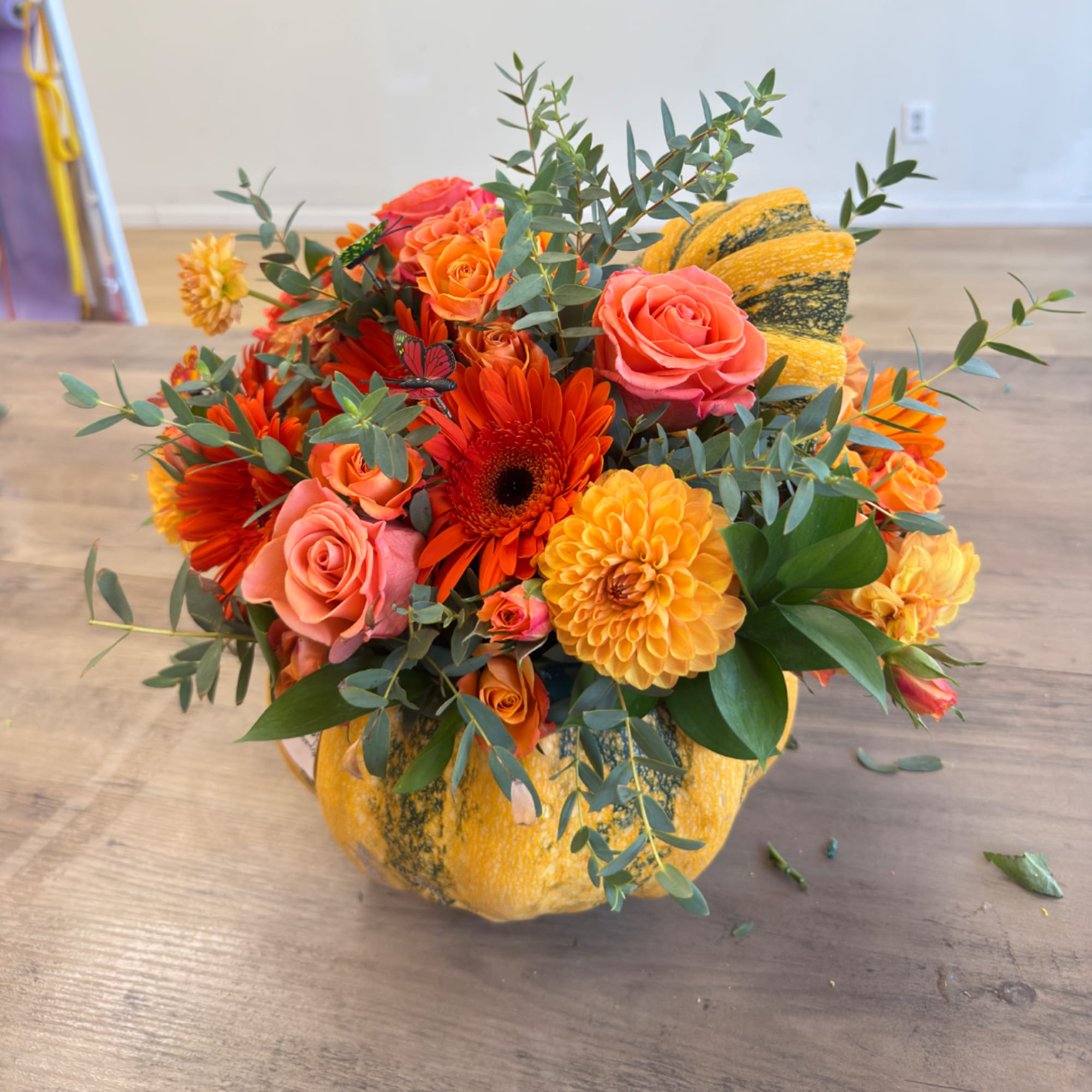 Orange and pink flower arrangement in a pumpkin container