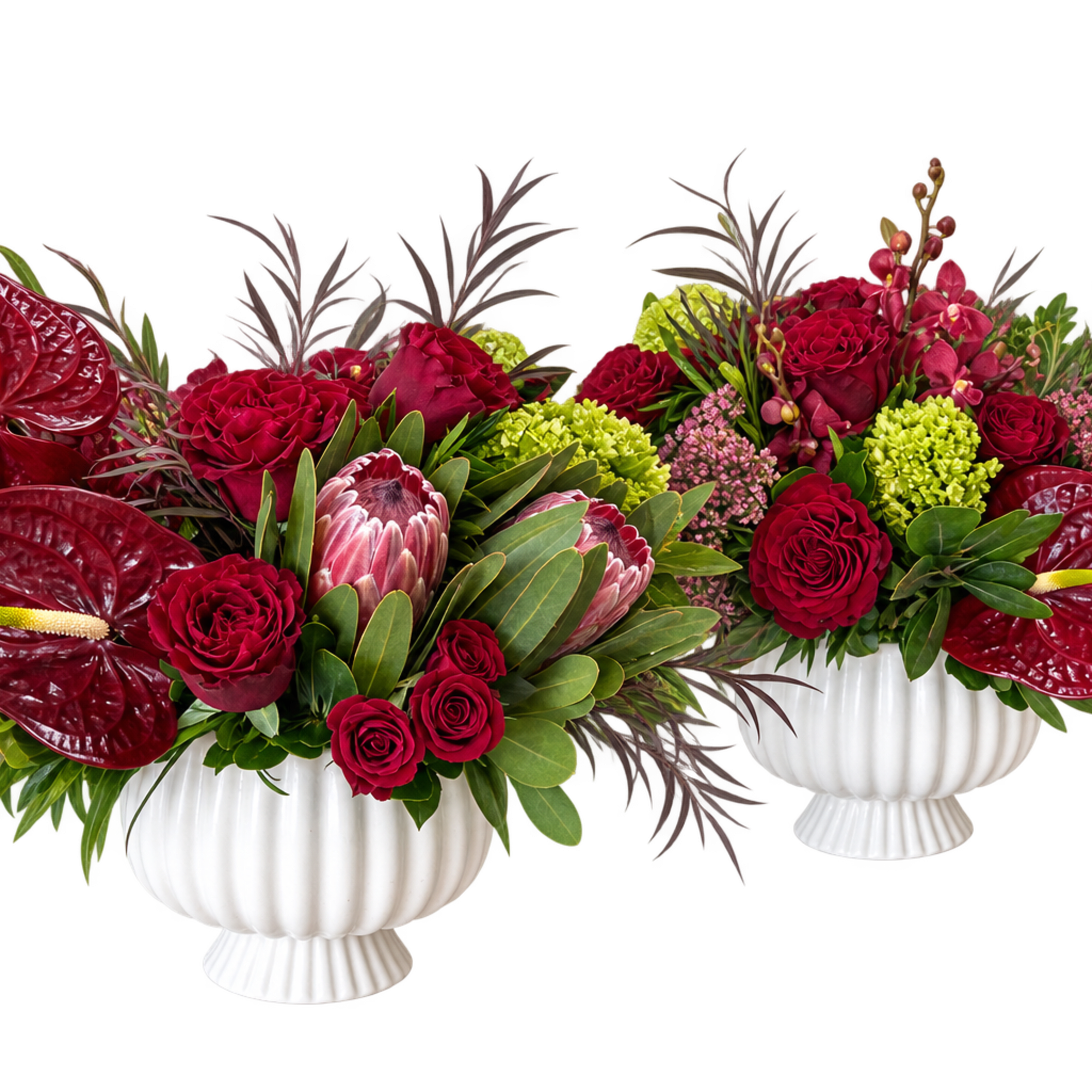 Two red floral arrangements in white urns with large anthuriums and roses