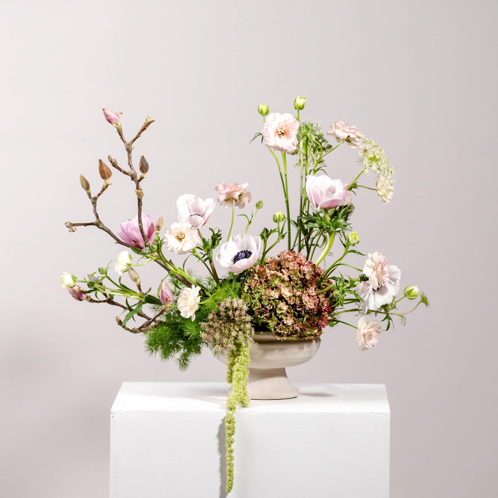 Pastel floral arrangement in a shallow pedestal vase with branching stems