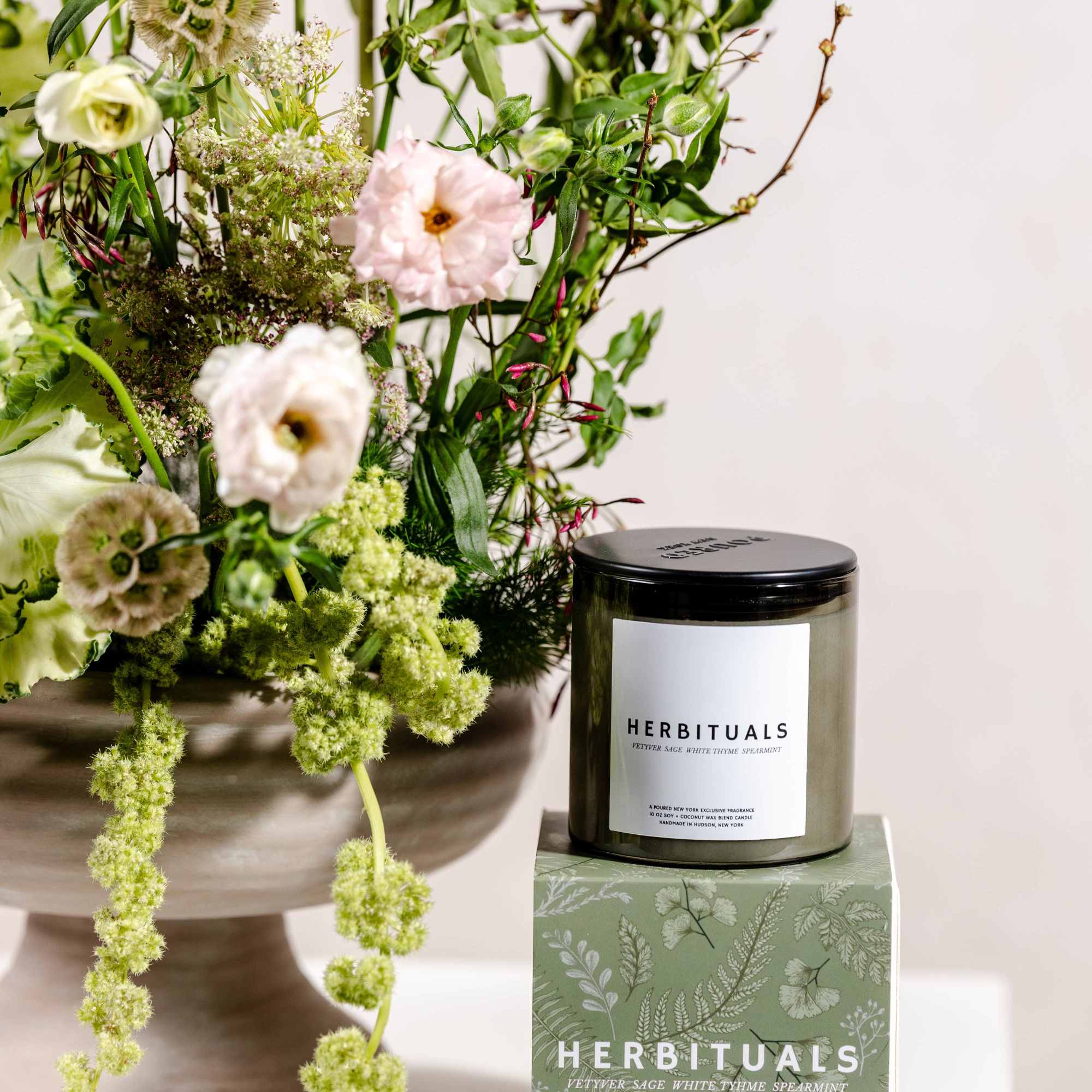 Floral arrangement beside a candle jar and box