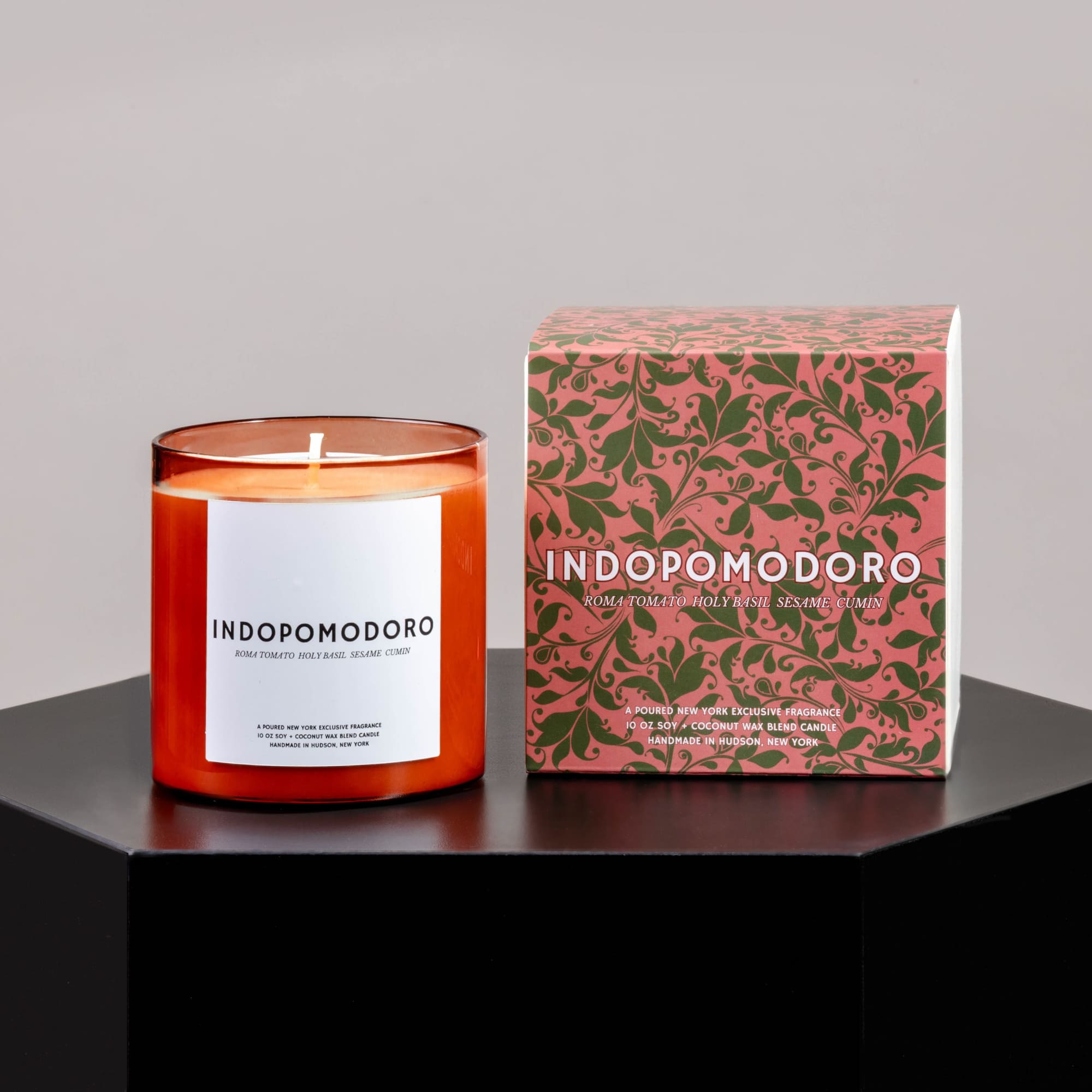 Orange candle in a glass jar beside its patterned box