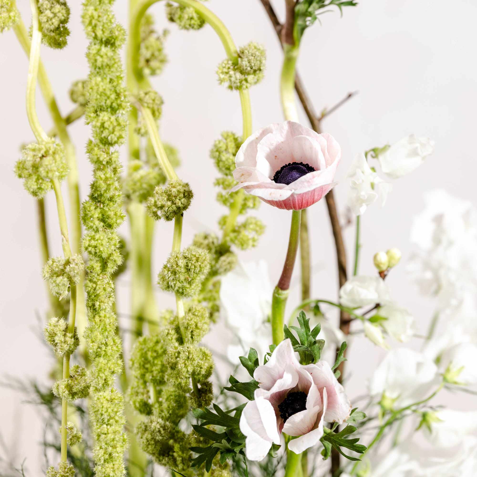 Tall floral arrangement with pale pink anemones and white blooms