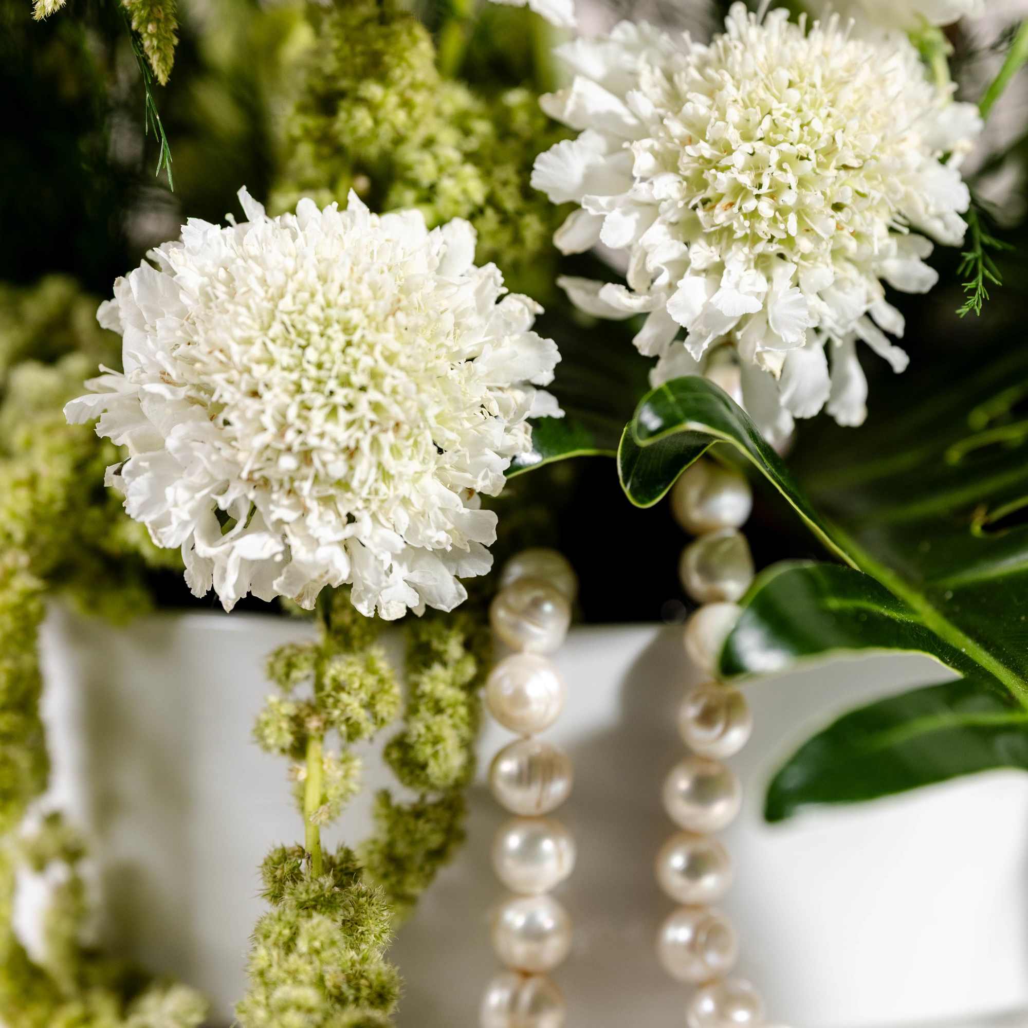 White flowers with pearl strands in a white vase