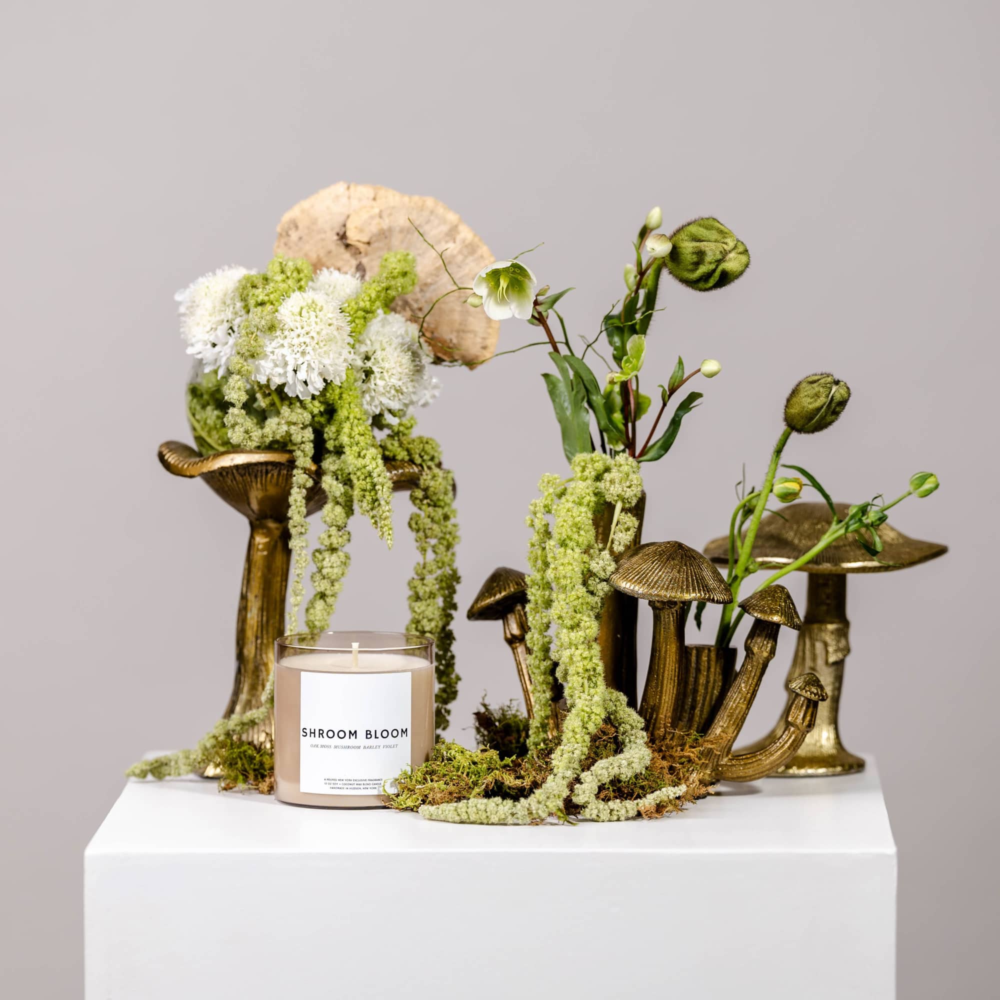 Mushroom-shaped floral arrangement with a candle on a white pedestal