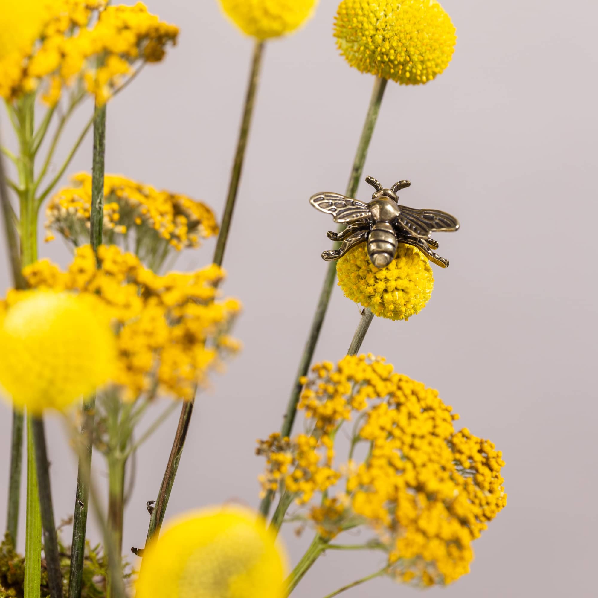 Yellow billy ball flowers with a bee ornament