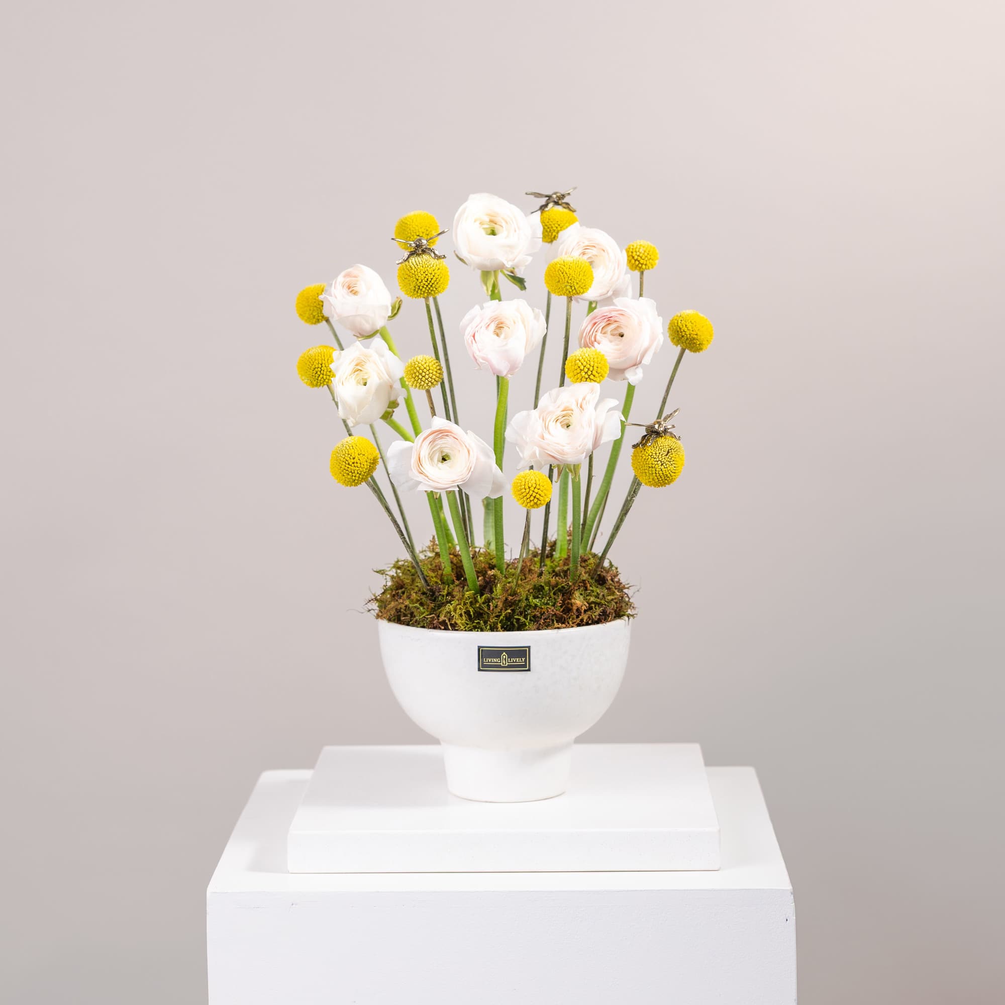 White and yellow floral arrangement in a white pedestal vase