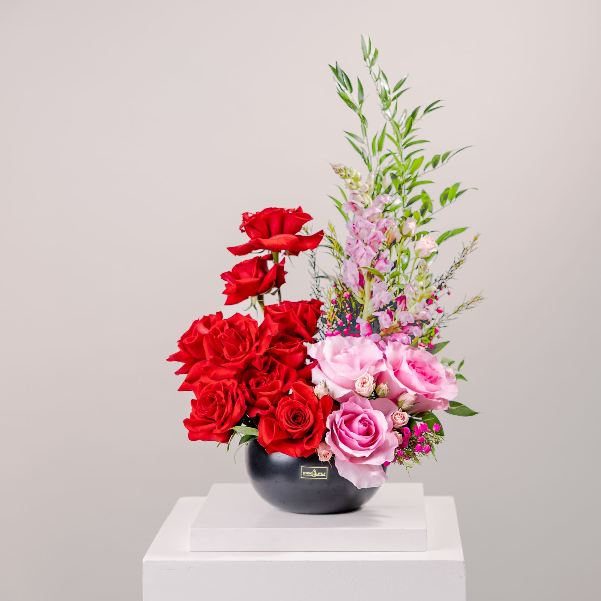 Red and pink roses arranged in a black vase