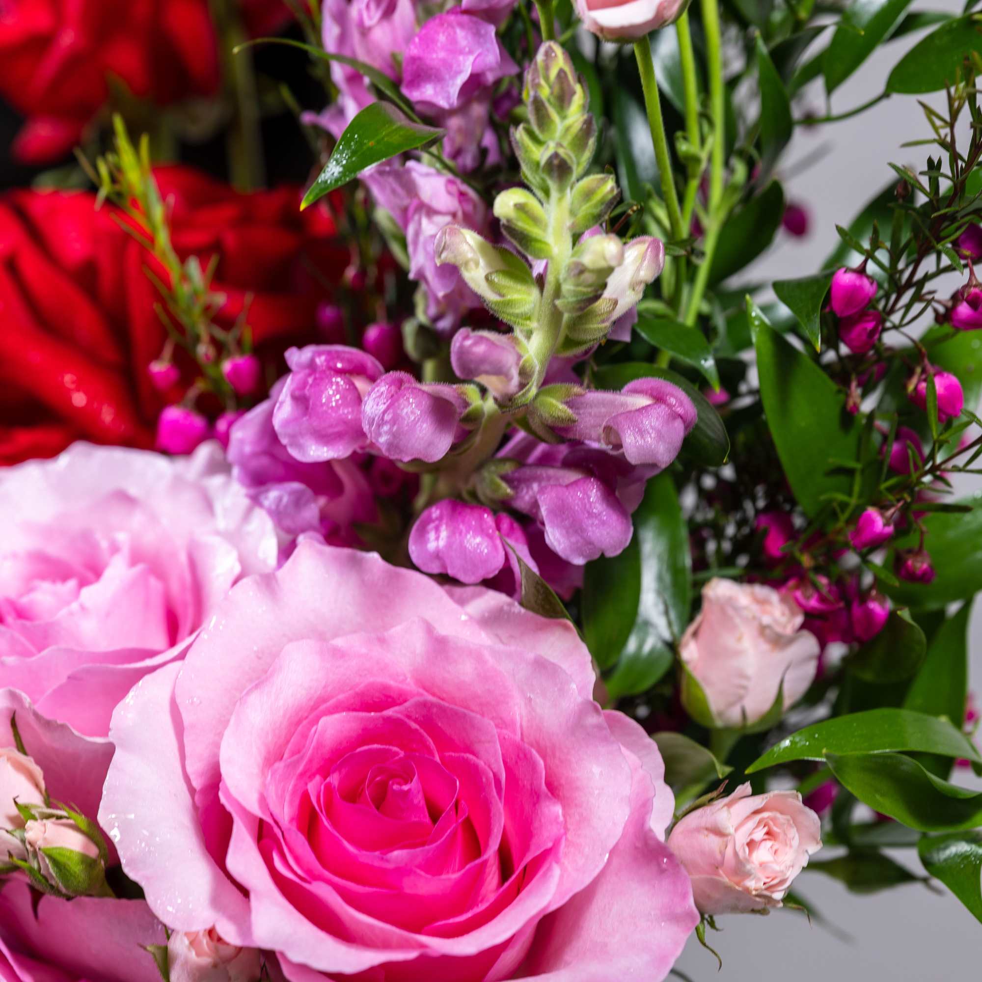 Pink and lavender roses with purple snapdragons and greenery