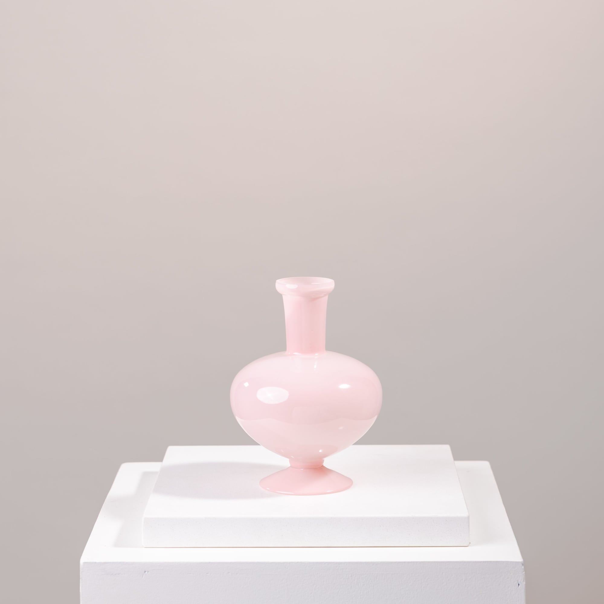Pink glass vase on a white pedestal
