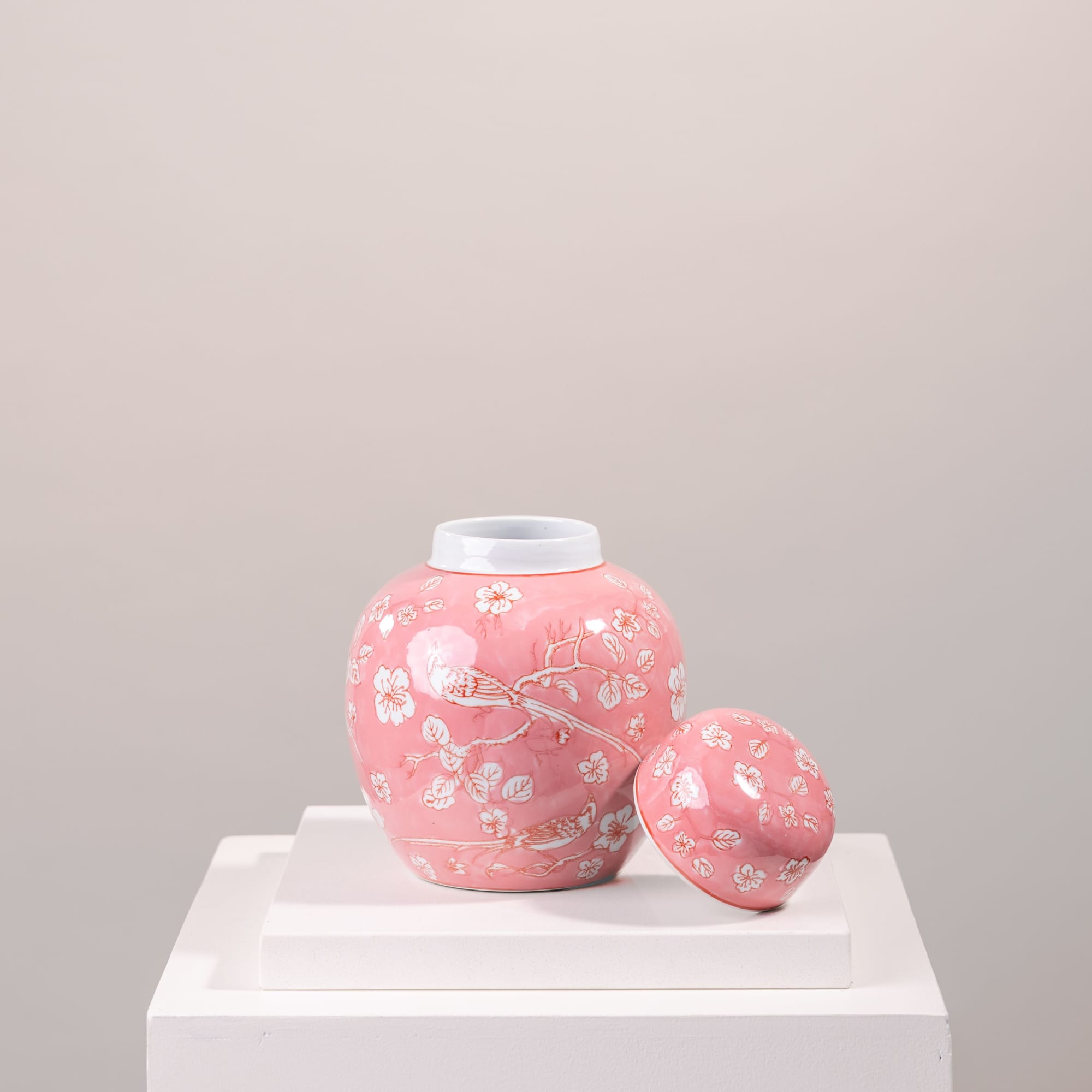 Pink floral ceramic jar with matching lid on a white pedestal