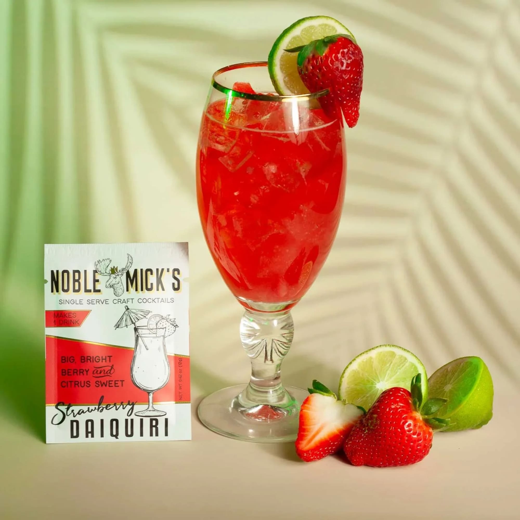 Strawberry daiquiri in a stemmed glass with lime and strawberry garnish