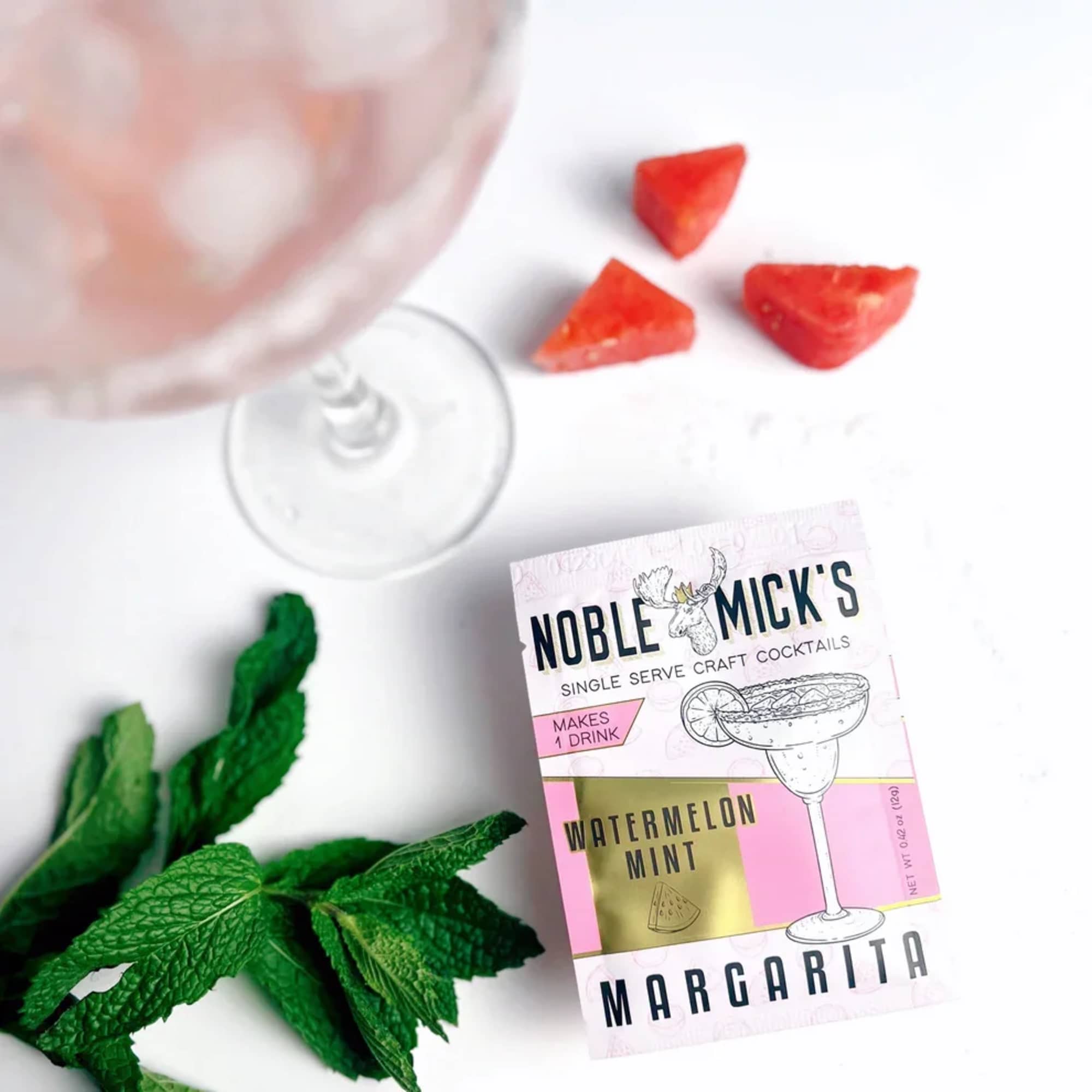 Cocktail mix packet beside mint leaves and strawberry pieces