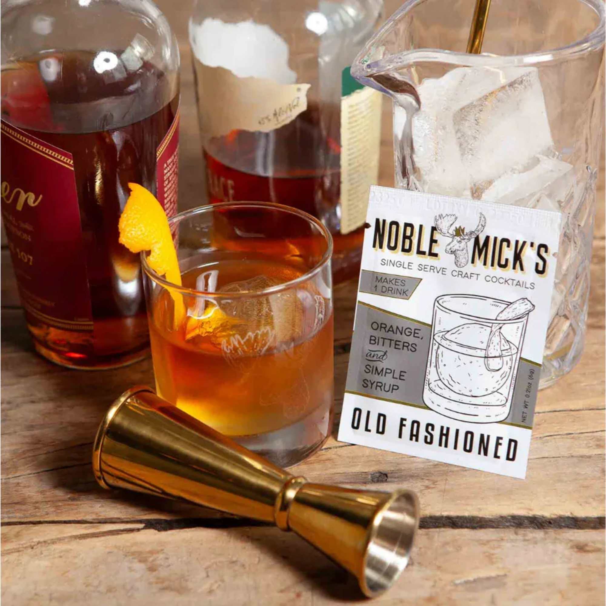 Cocktail kit with whiskey bottles, a glass of old fashioned, and a jigger