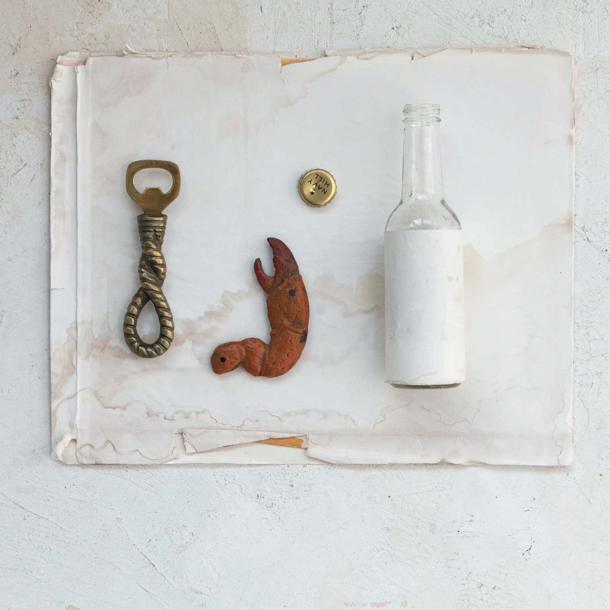 A bottle, bottle cap, and two small metal objects arranged on white paper.