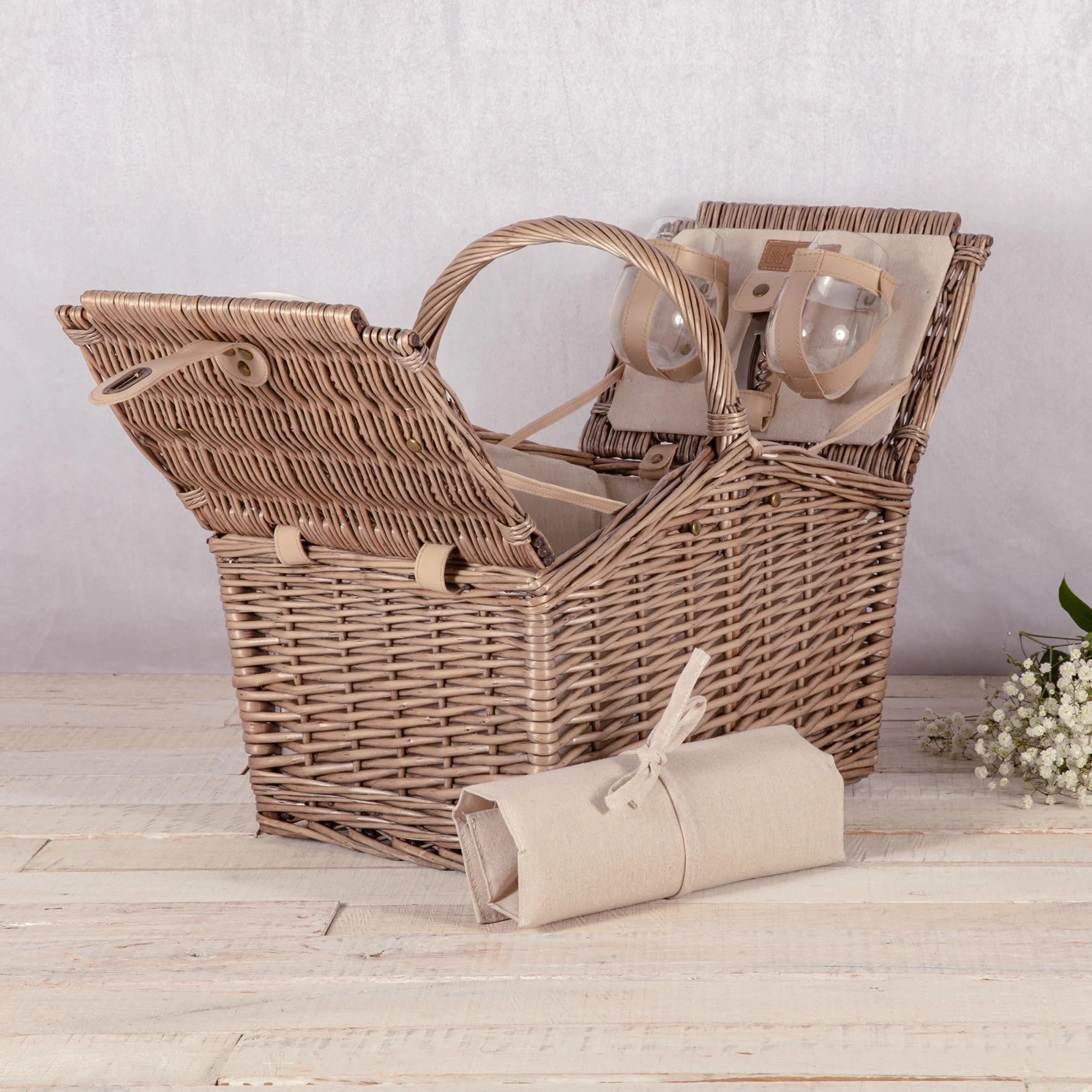 Wicker picnic basket with plates and glasses, plus a rolled napkin