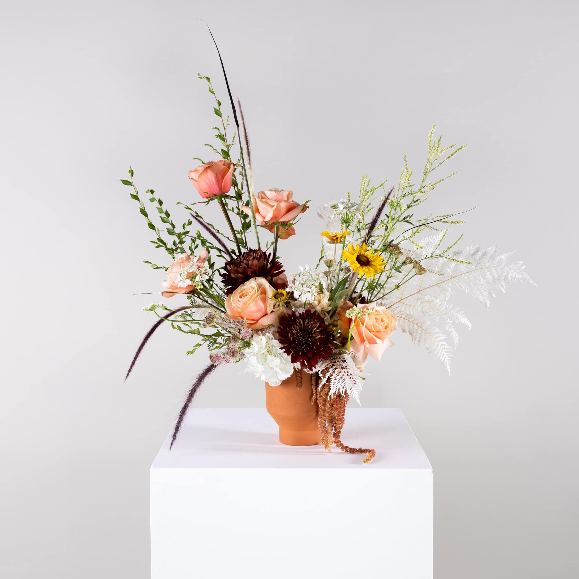 Peach and burgundy floral arrangement in a terracotta vase