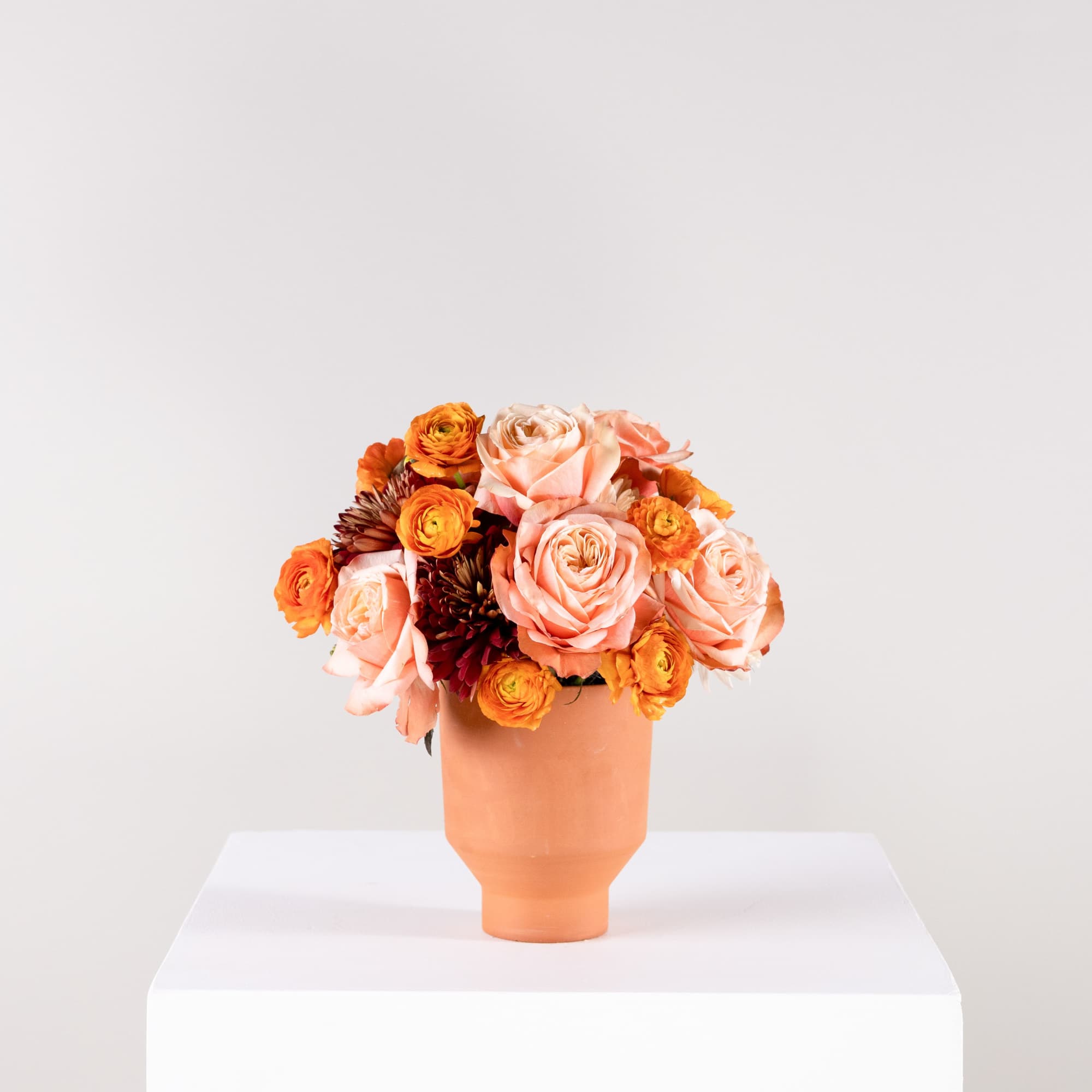 Peach and orange roses arranged in a peach vase