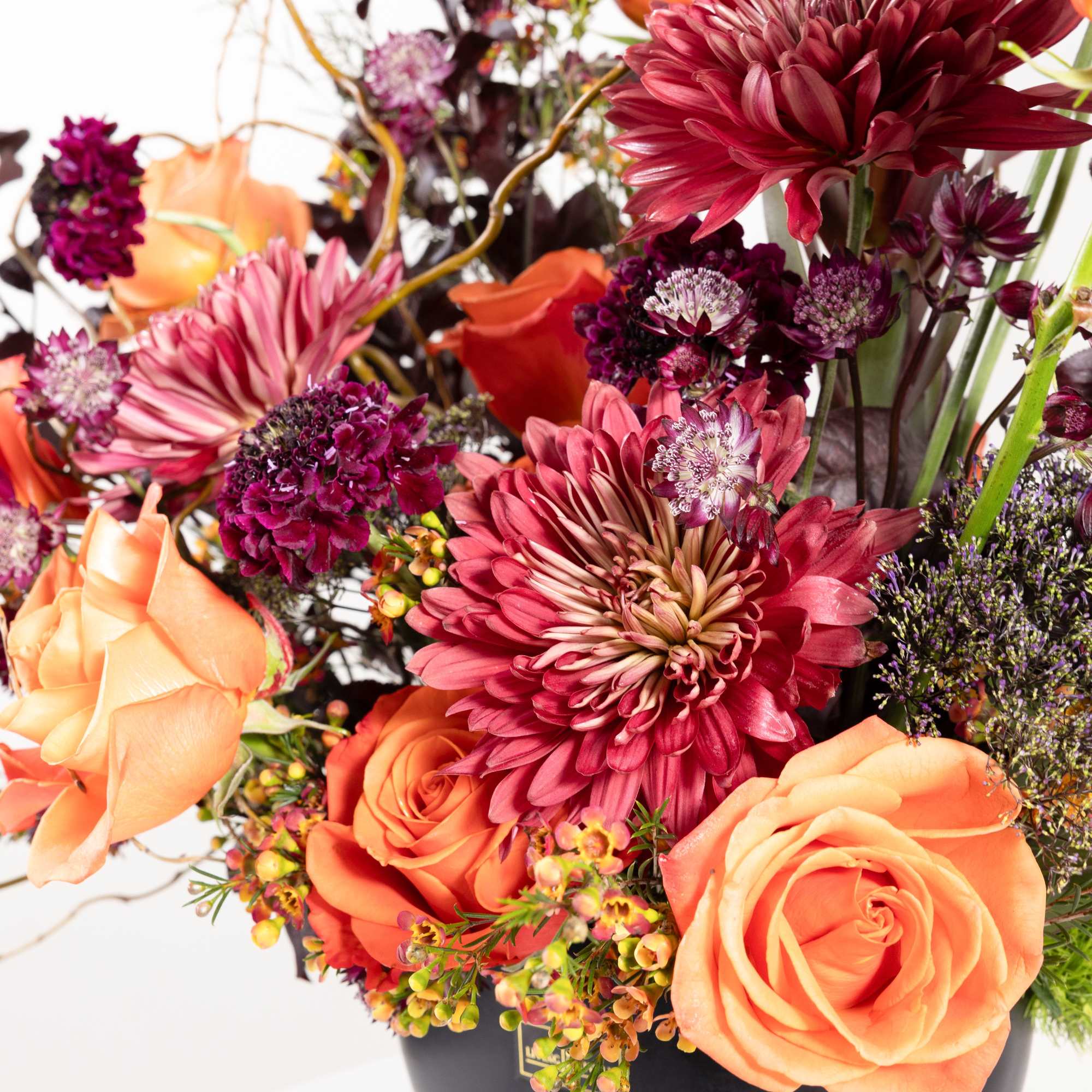 Orange roses and burgundy chrysanthemums in a black vase
