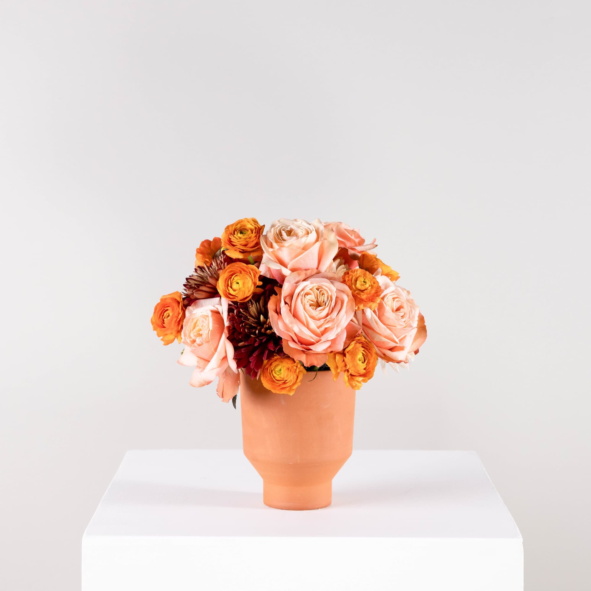 Peach and orange rose bouquet in a terracotta vase