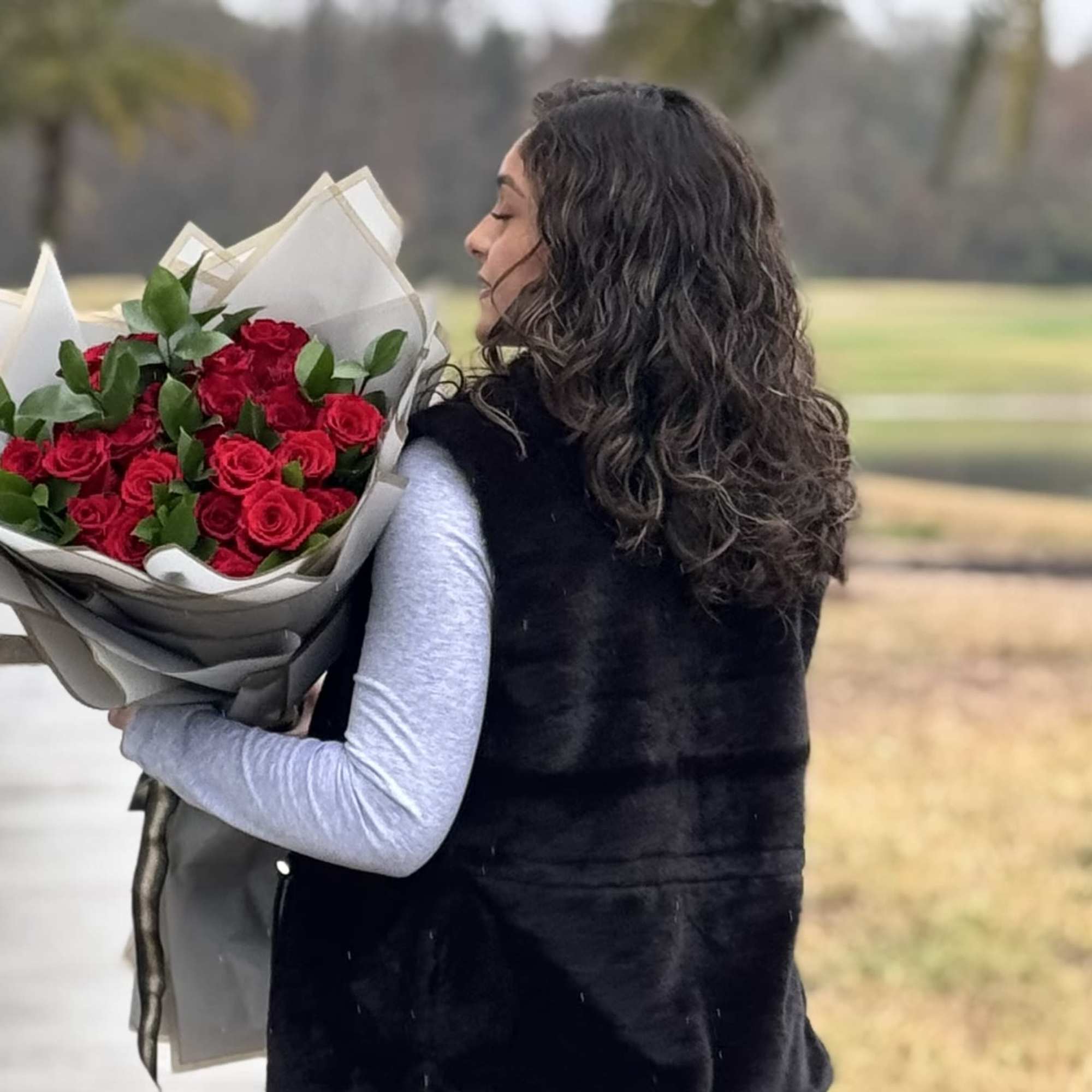Woman holding a bouquet of red roses wrapped in paper