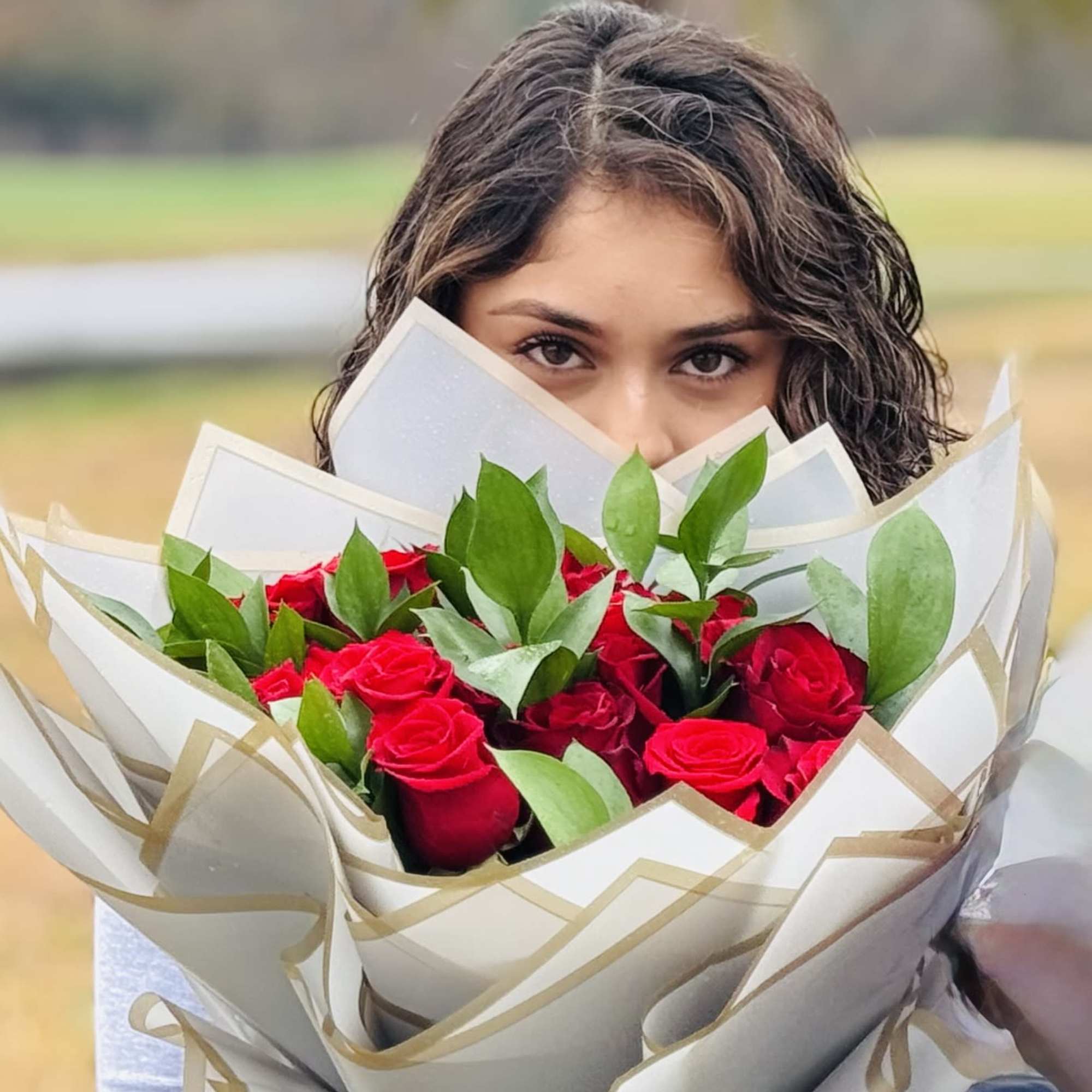 Woman holding a bouquet of red roses wrapped in white paper