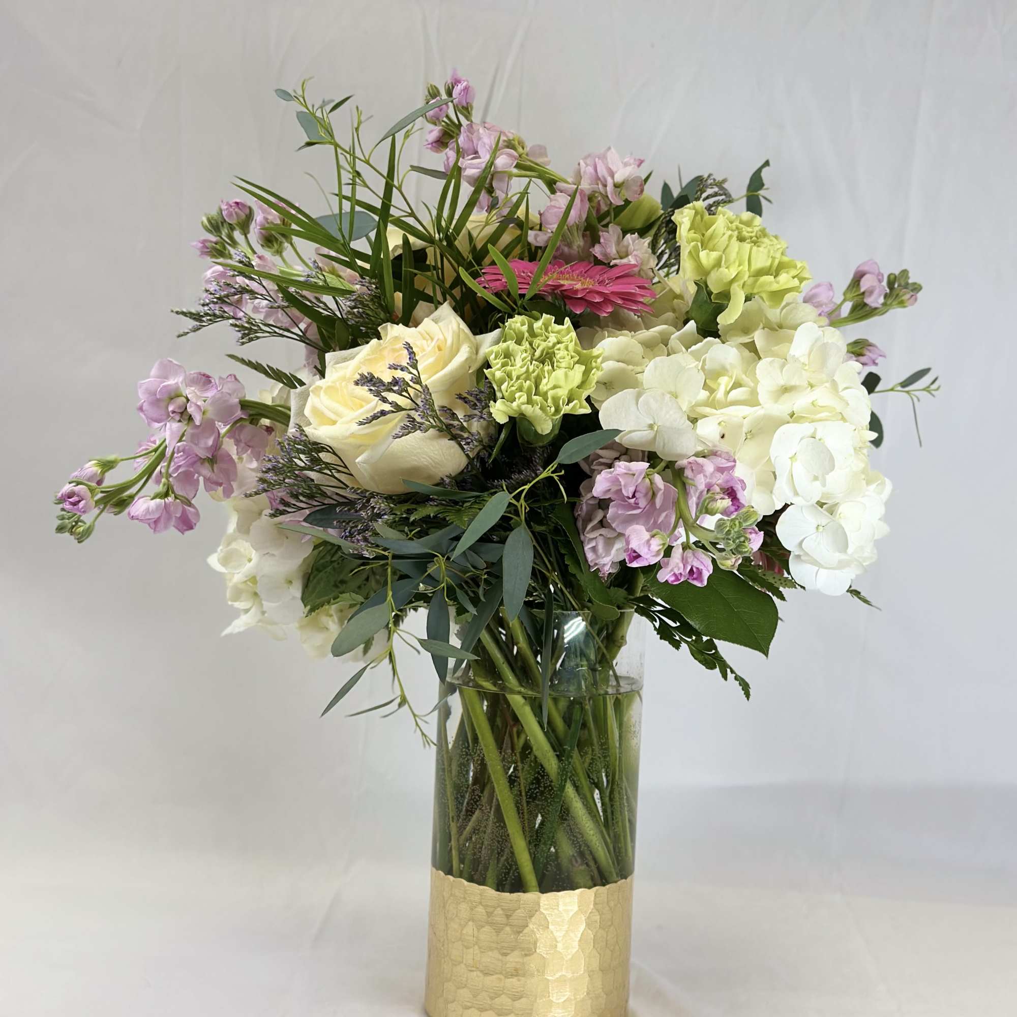 Mixed bouquet in a gold vase with white, pink, and green flowers