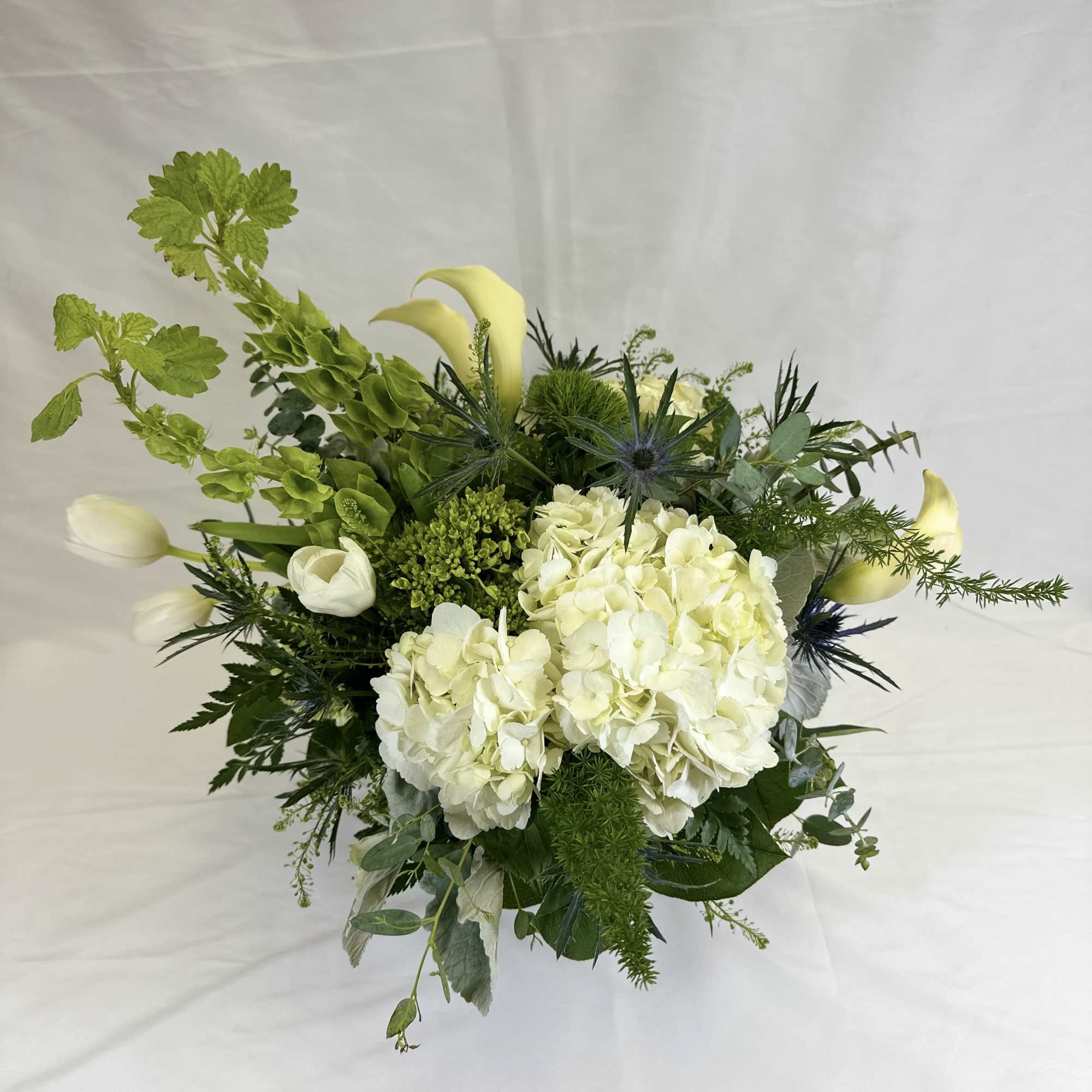 White hydrangeas and calla lilies in a green bouquet