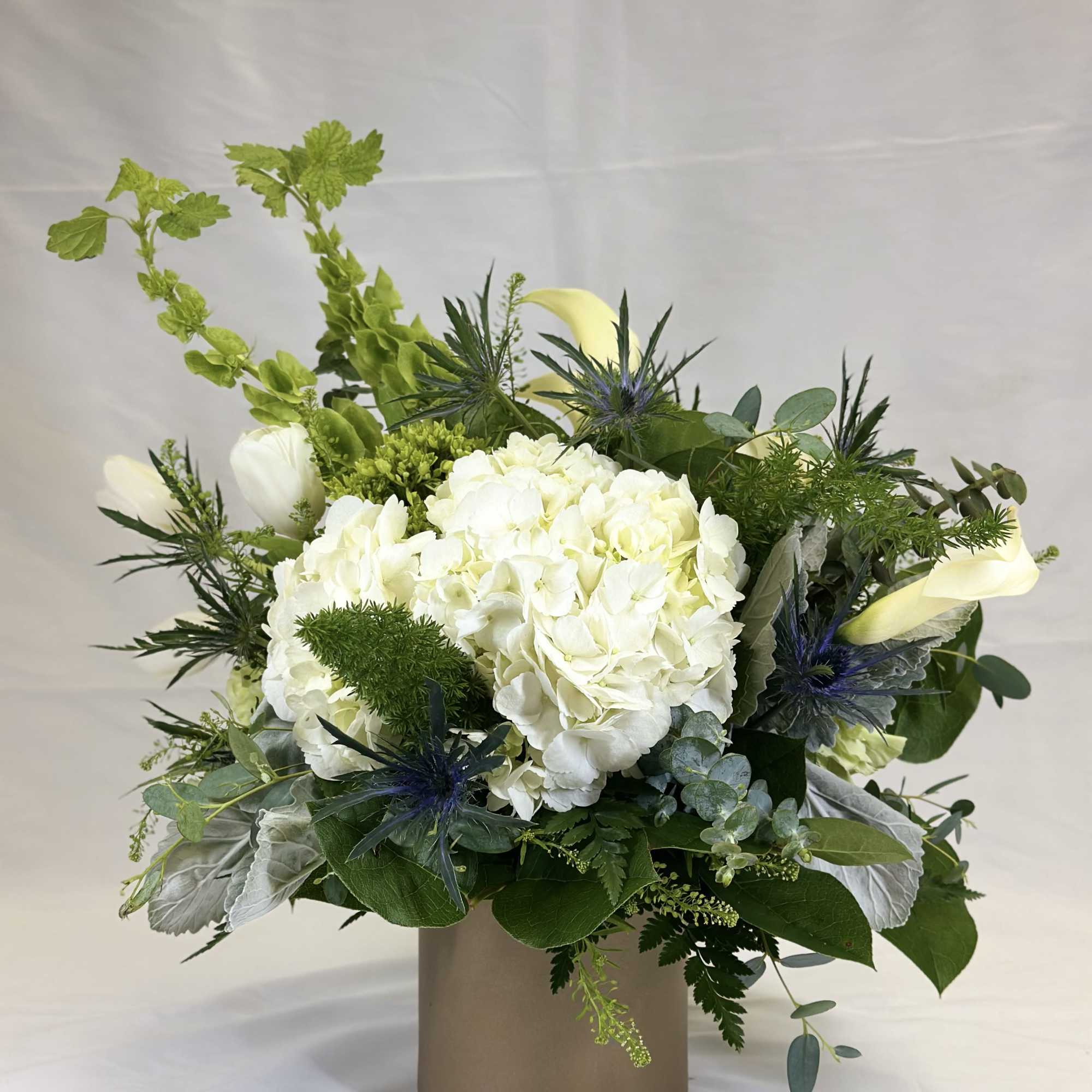 White hydrangea and calla lily arrangement in a taupe vase