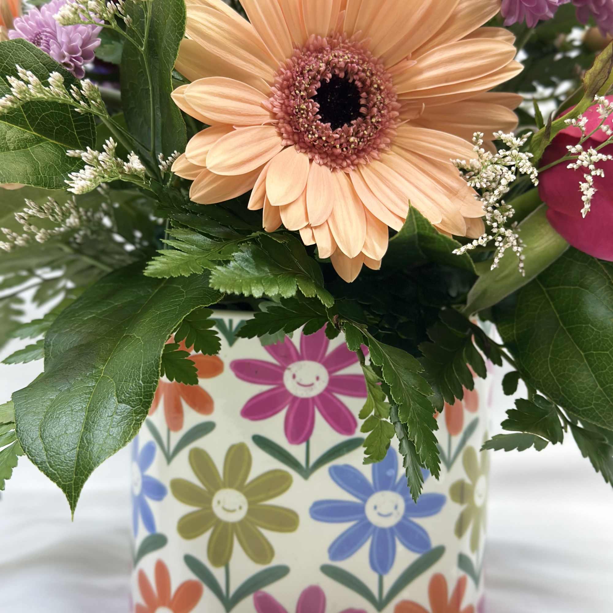 Peach gerbera daisy bouquet in a patterned ceramic vase