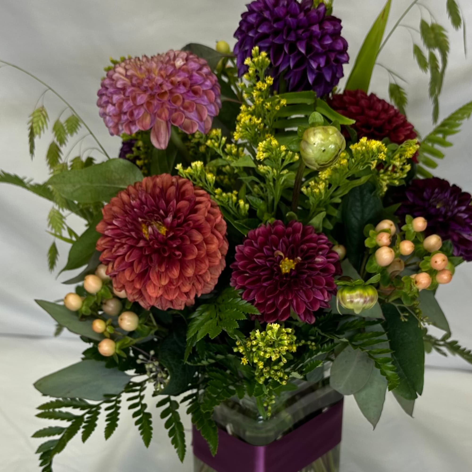 Mixed bouquet of purple and pink dahlias in a glass vase