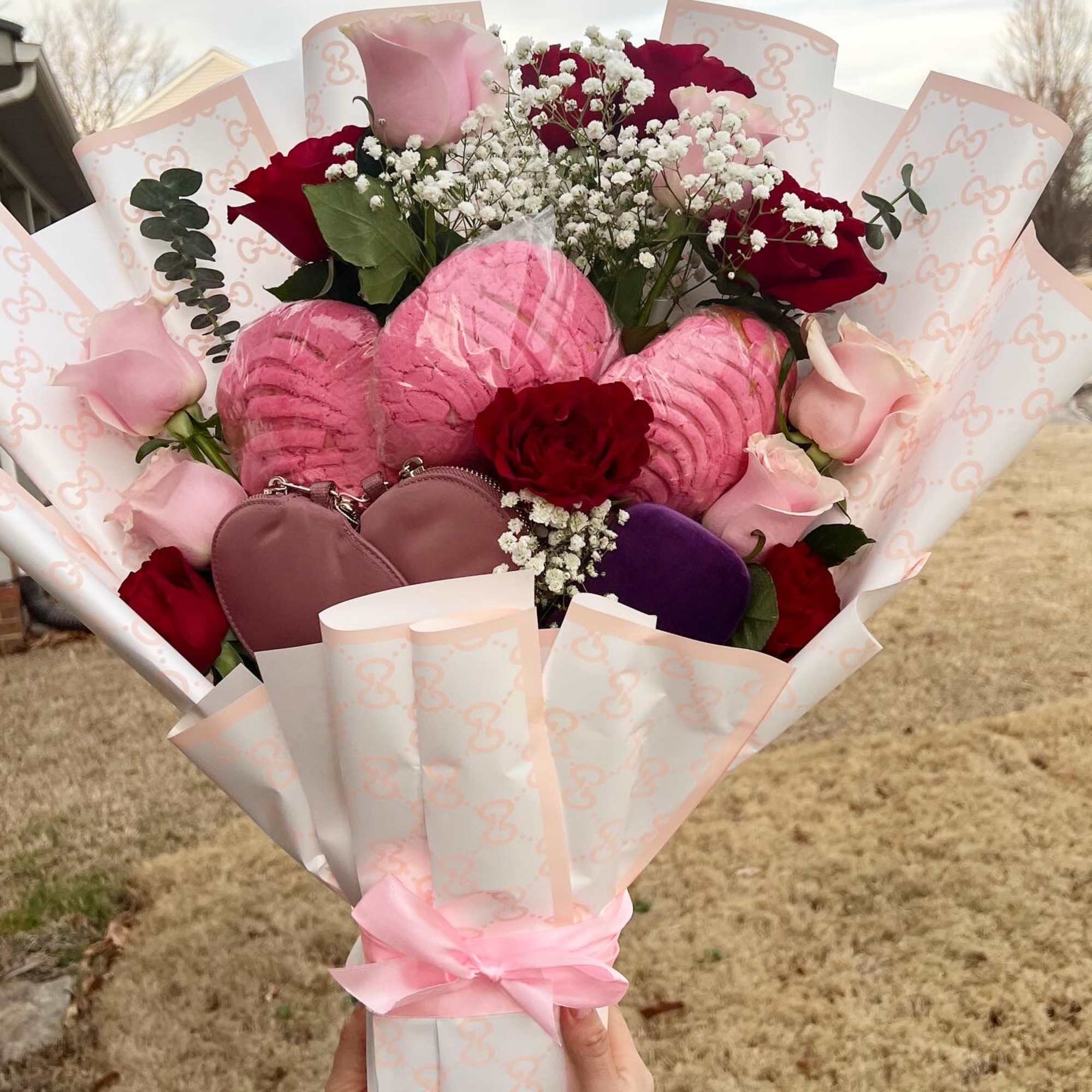 Bouquet of pink and red roses with baby’s breath and heart-shaped gifts