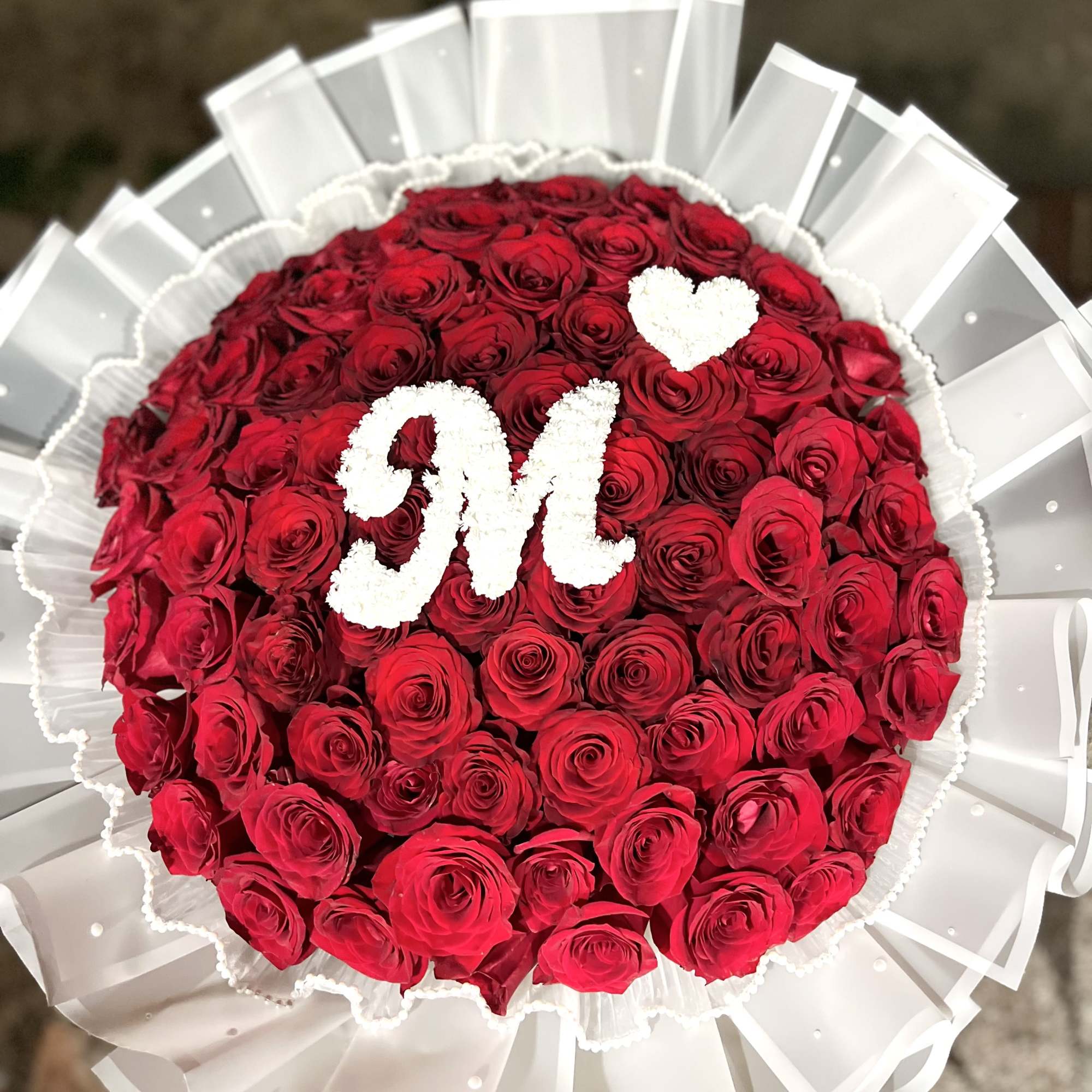 Round bouquet of red roses with white initials and a heart
