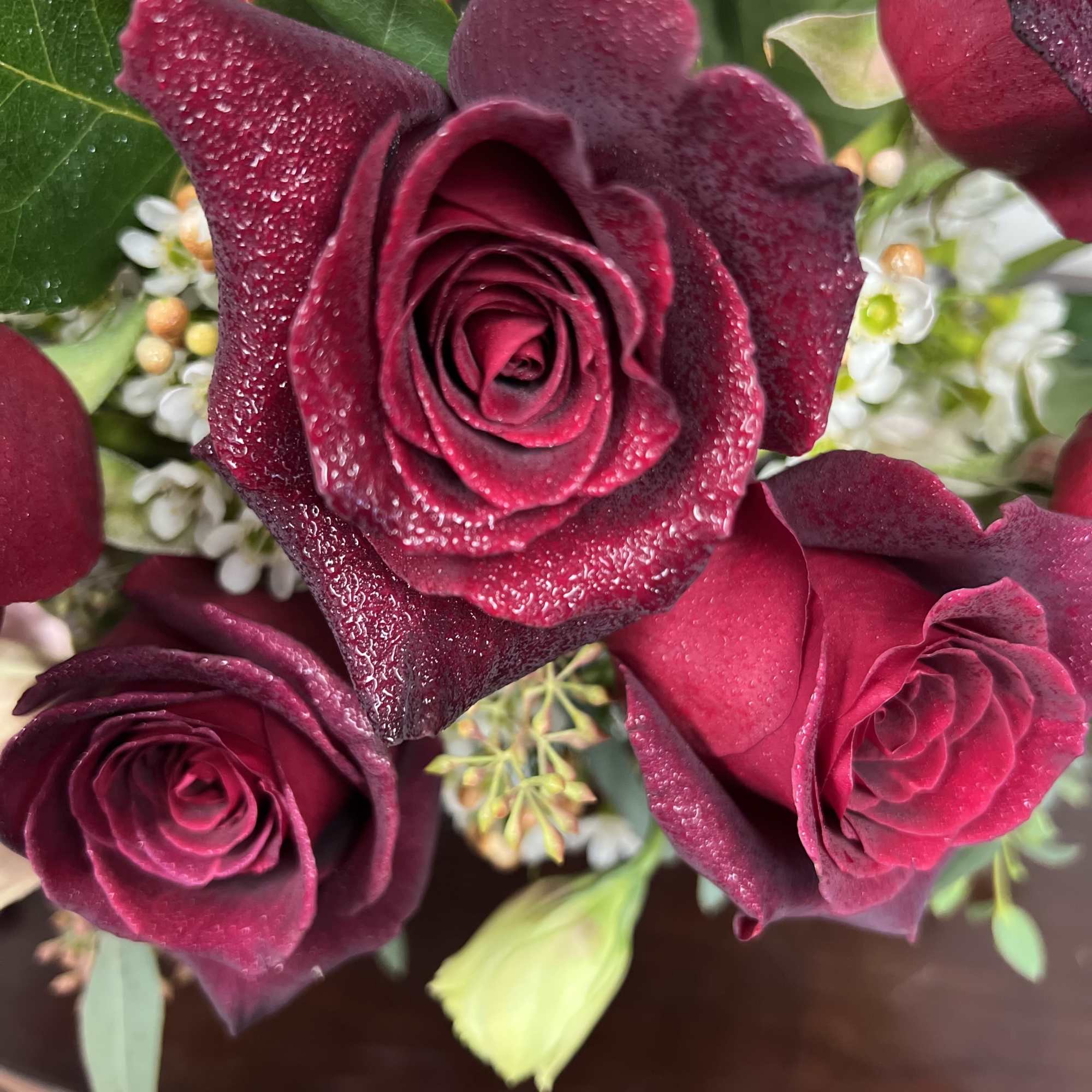 Close-up bouquet of deep red roses with small white filler flowers