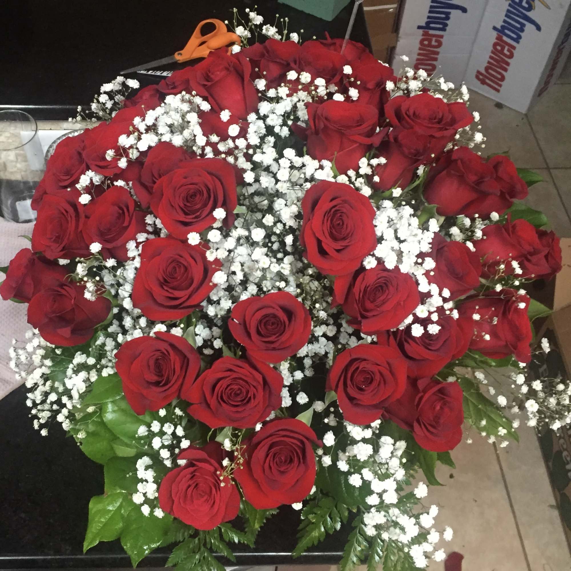 Large round bouquet of red roses with white filler flowers in a dome shape