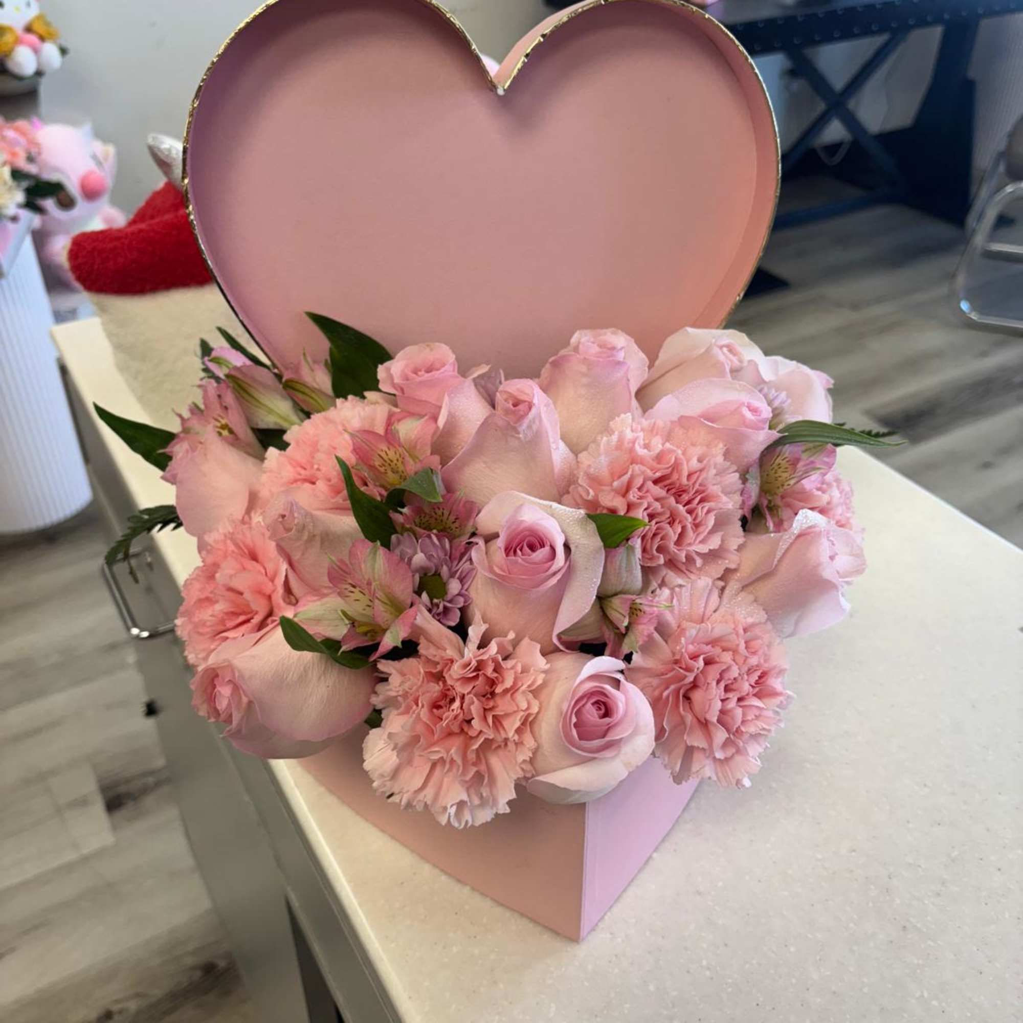 Pink roses and carnations arranged in a heart-shaped box