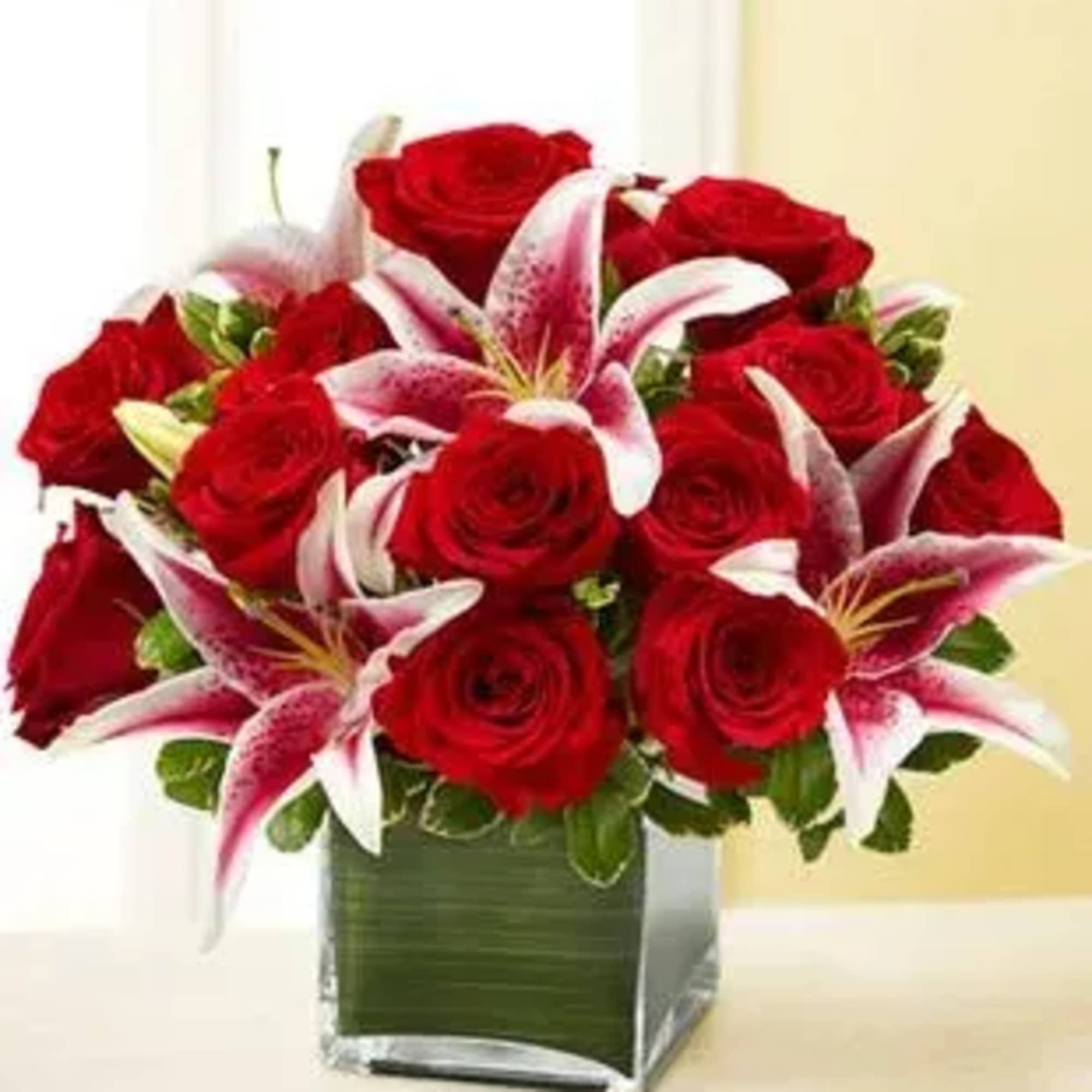 Red roses and pink lilies in a square glass vase