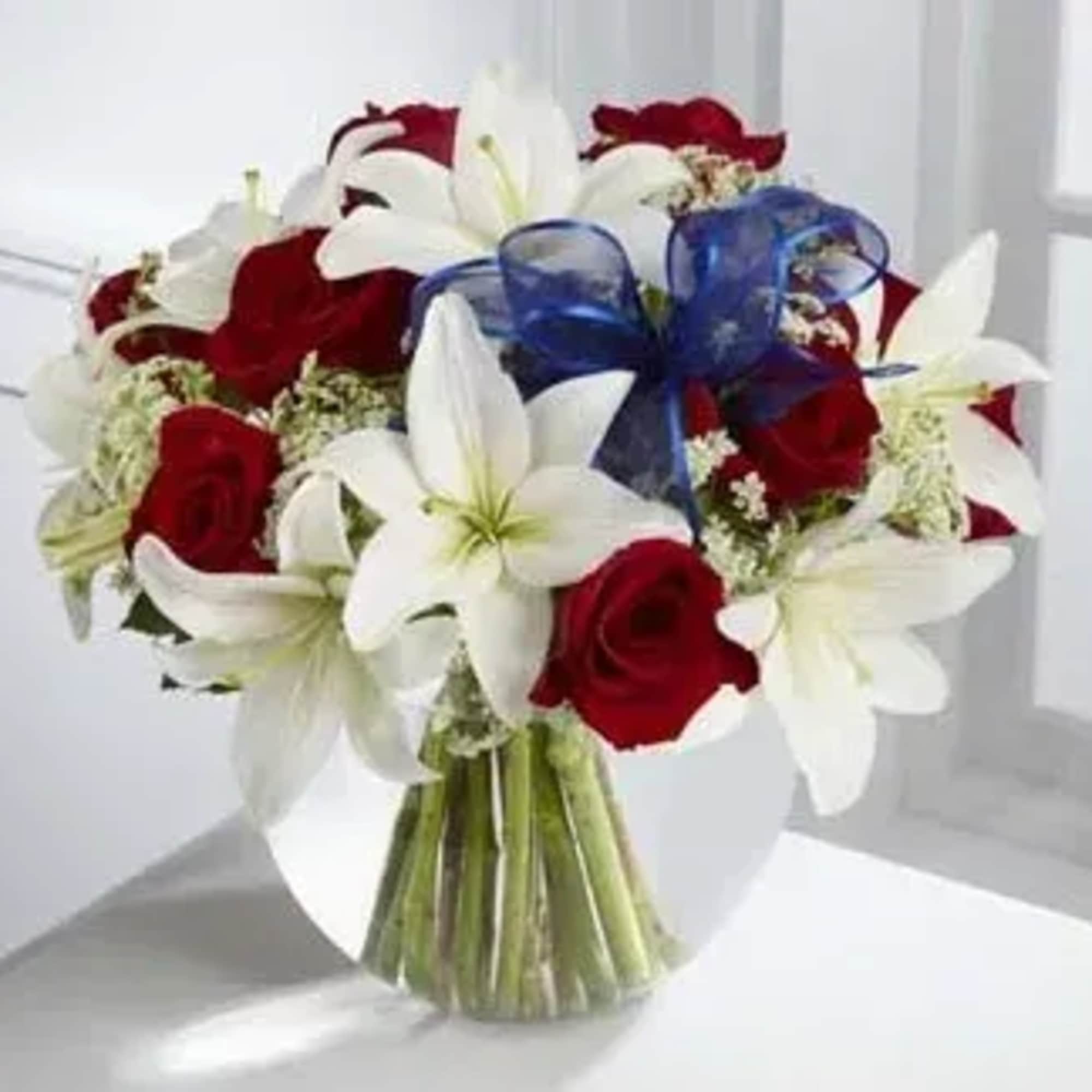 Bouquet of red roses and white lilies with a blue ribbon in a glass vase