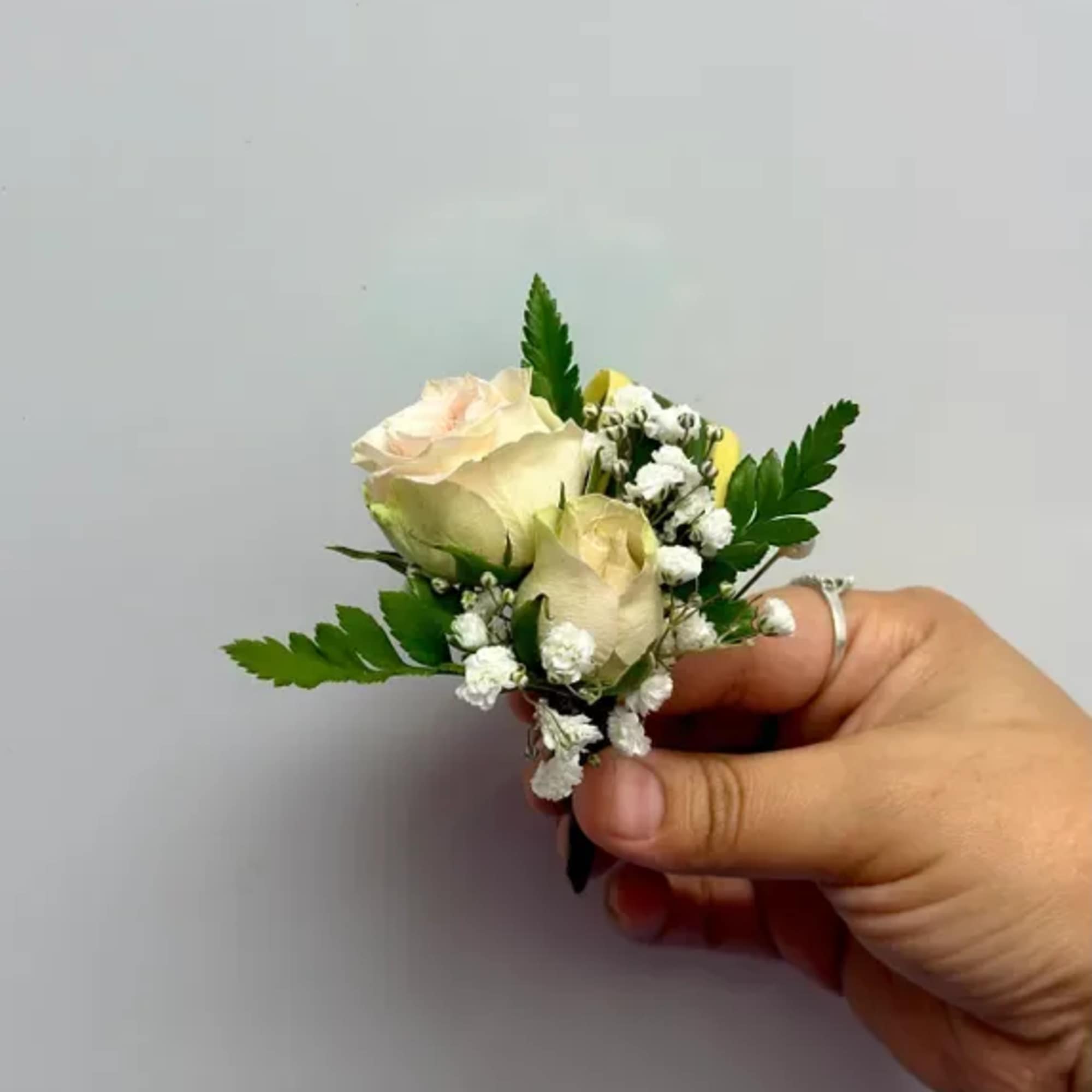 Small cream rose boutonniere with white filler flowers and greenery, photo 4 of 4