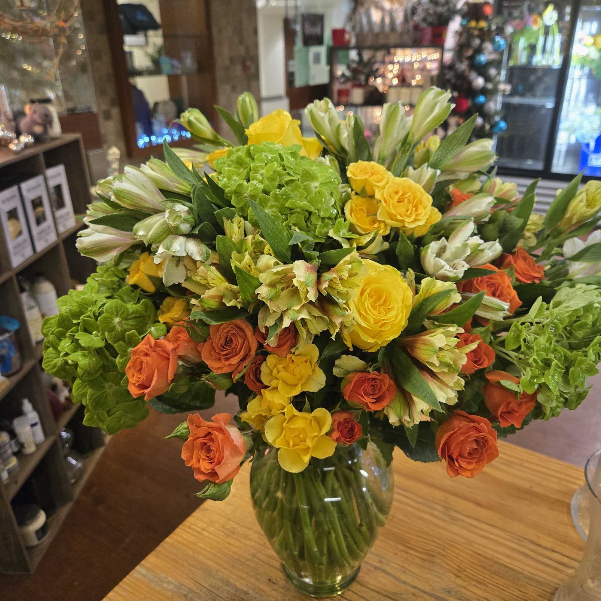 Bouquet of yellow and orange roses with green hydrangeas in a glass vase, photo 2 of 2