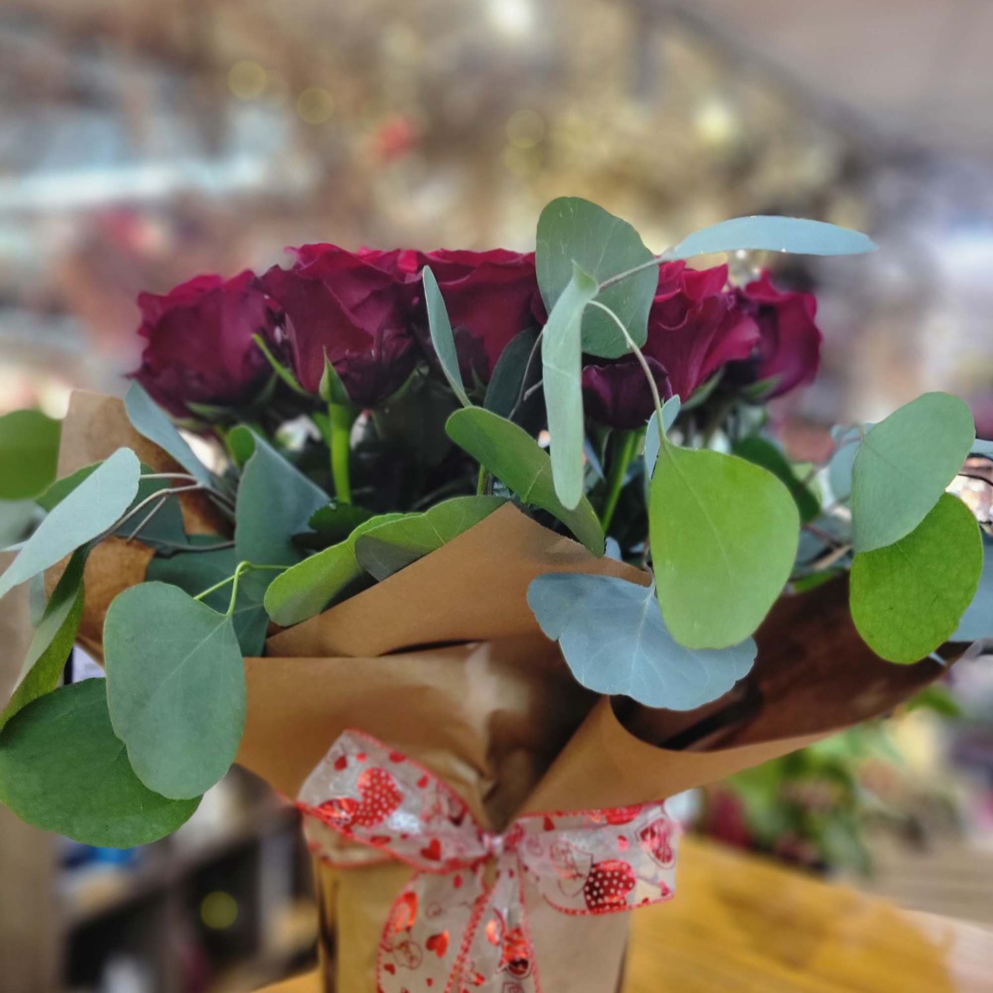 Bouquet of dark red roses with eucalyptus in brown paper wrap